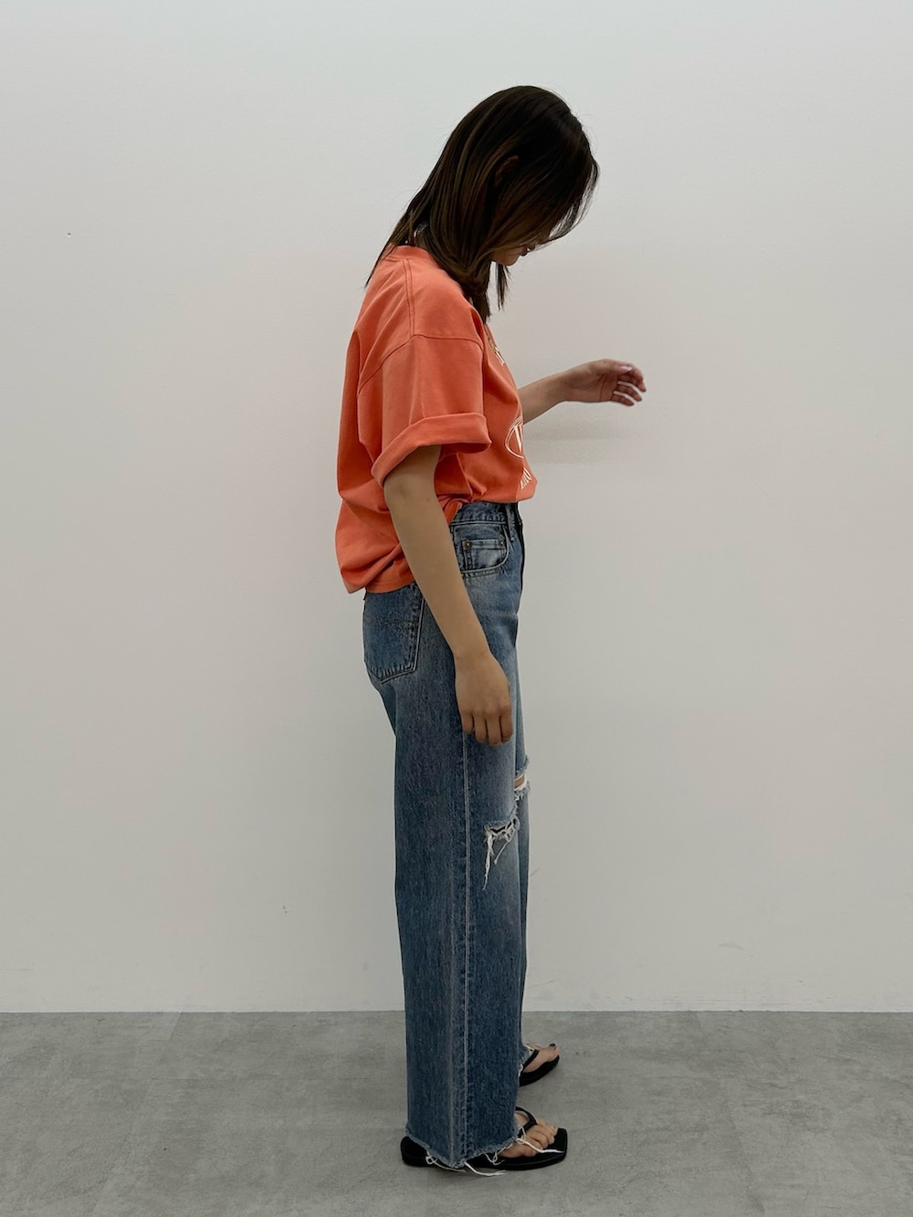 ブルー系のデニムパンツ、オレンジ系のTシャツ/カットソー、ブラック系のサンダルを着用したレディースの春コーディネートの2枚目の写真