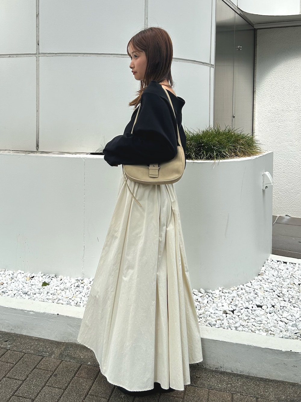 ブラック系のスウェット、ホワイト系のスカート、ブラック系のブーツを着用したレディースの秋コーディネートの2枚目の写真