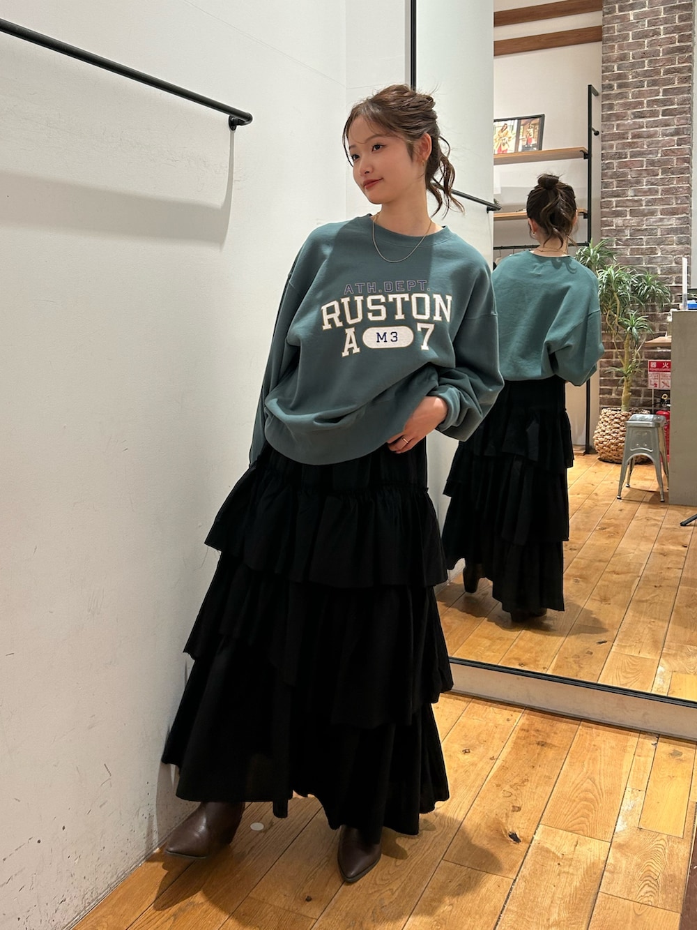 グリーン系のスウェット、ブラック系のスカートを着用したレディースの冬コーディネートの2枚目の写真