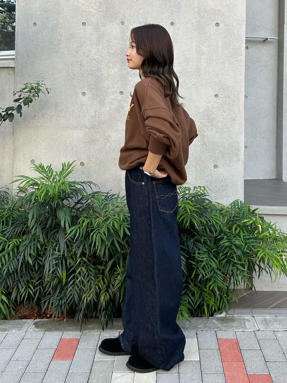 ブルー系のデニムパンツ、ブラック系のスリッポン、ブラウン系のスウェットを着用したレディースの冬コーディネートの3枚目の写真