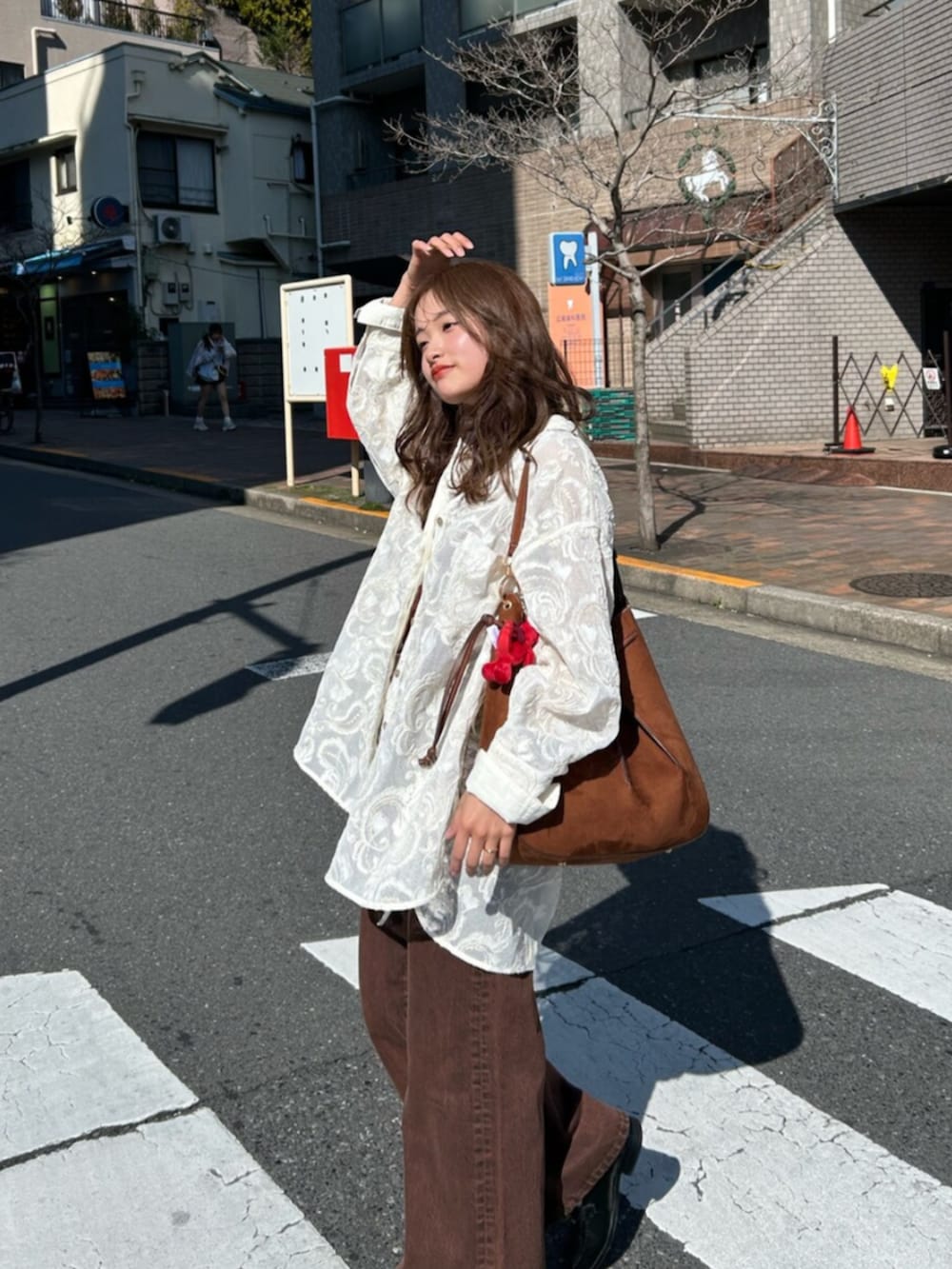 ブラウン系のキャミソール、ホワイト系のシャツ/ブラウス、ブラウン系のデニムパンツを着用したレディースの春コーディネートの6枚目の写真