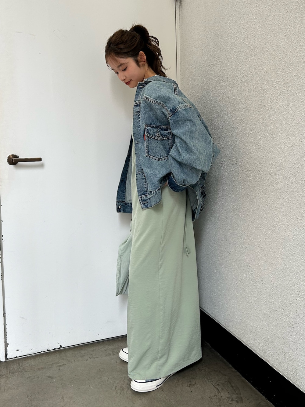 グリーン系のトートバッグ、ブルー系のスニーカー、ブルー系のデニムジャケットを着用したレディースの春コーディネートの2枚目の写真
