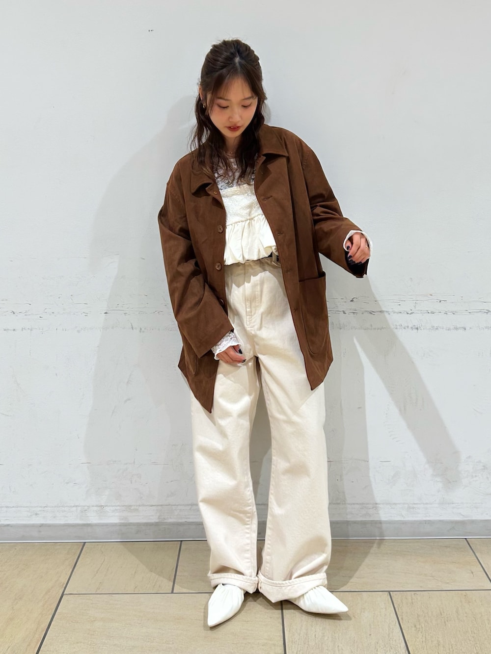 ブラウン系のテーラードジャケット、ホワイト系のパンプス、ホワイト系のデニムパンツを着用したレディースの冬コーディネートの2枚目の写真