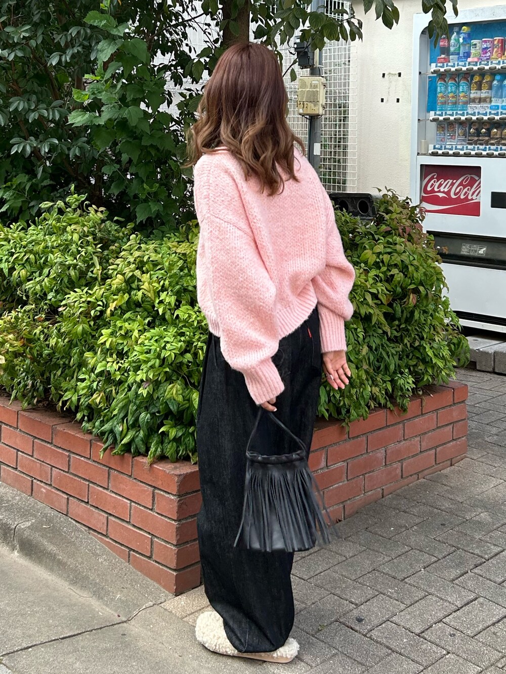 ピンク系のニット/セーター、ブラック系のデニムパンツ、ブラック系のショルダーバッグを着用したレディースの秋コーディネートの2枚目の写真