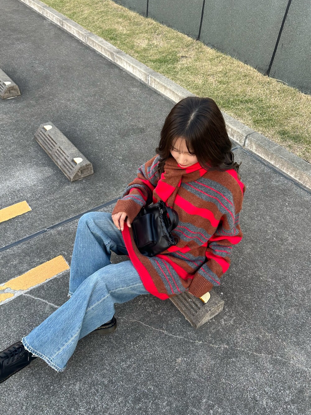 レッド系のニット/セーター、ブルー系のデニムパンツ、ブラック系のショルダーバッグを着用したレディースの秋コーディネートの7枚目の写真