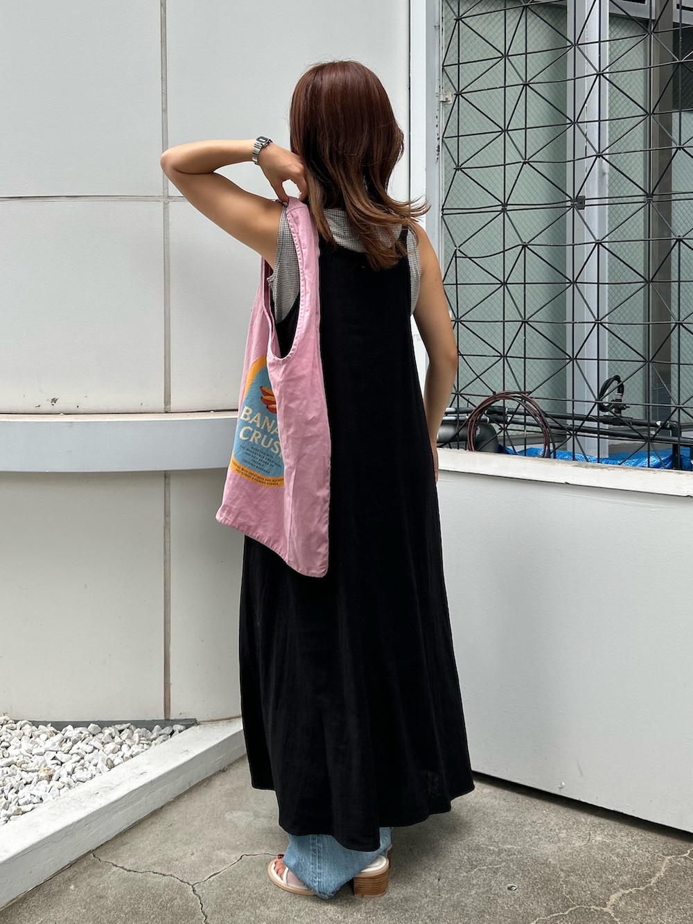 ブラック系のワンピース、ホワイト系のサンダル、ブルー系のデニムパンツを着用したレディースの夏コーディネートの4枚目の写真