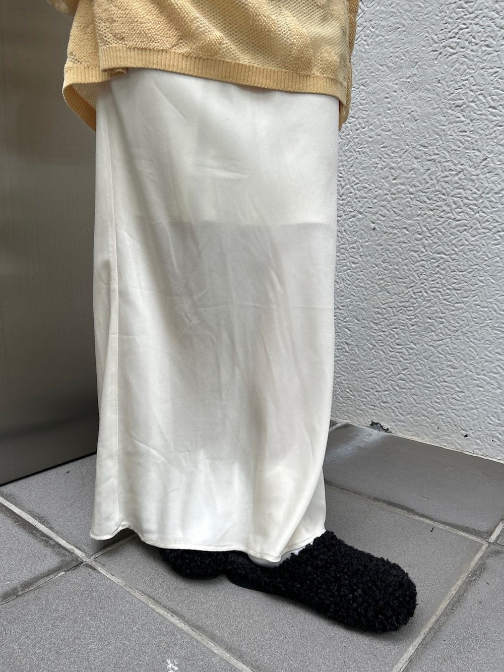 ブラック系のスリッポン、ホワイト系のハンドバッグ、イエロー系のニット/セーターを着用したレディースの冬コーディネートの5枚目の写真