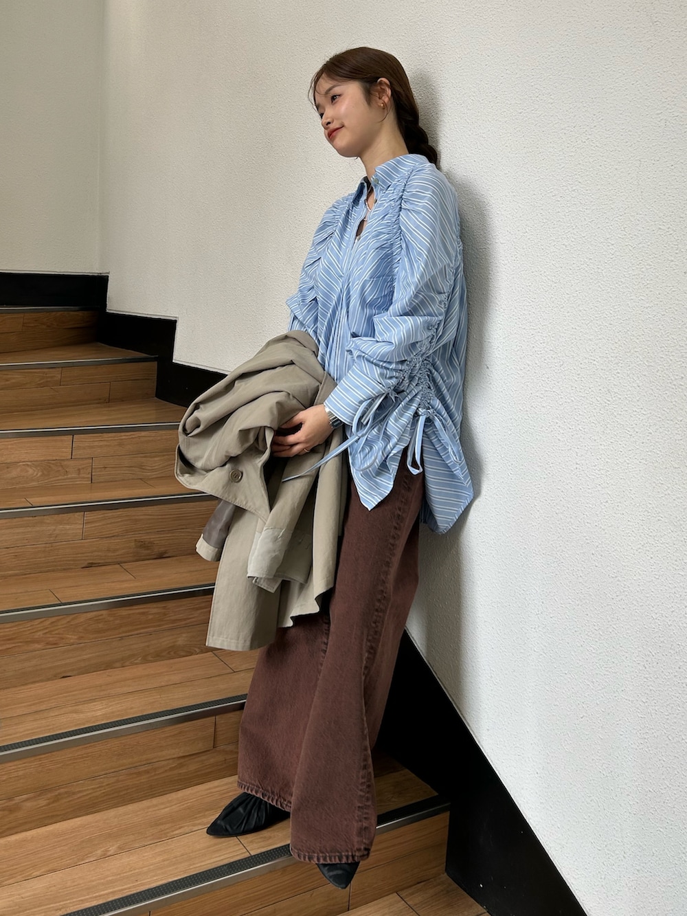 グリーン系のトレンチコート、ブラック系のパンプス、ブルー系のシャツ/ブラウスを着用したレディースの春コーディネートの2枚目の写真