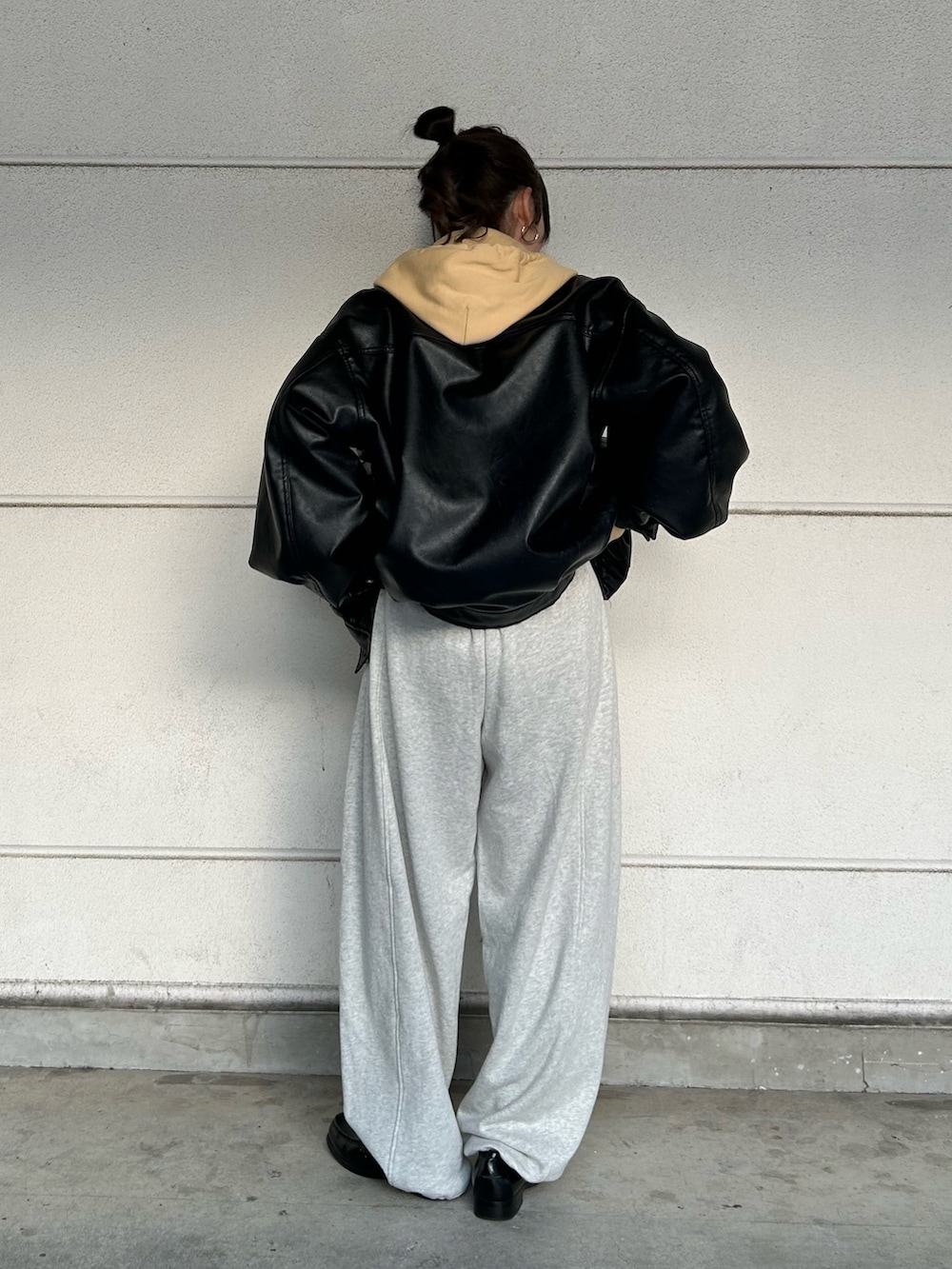 イエロー系のパーカー、ホワイト系のスウェットパンツ、ブラック系のブルゾンを着用したレディースの冬コーディネートの4枚目の写真