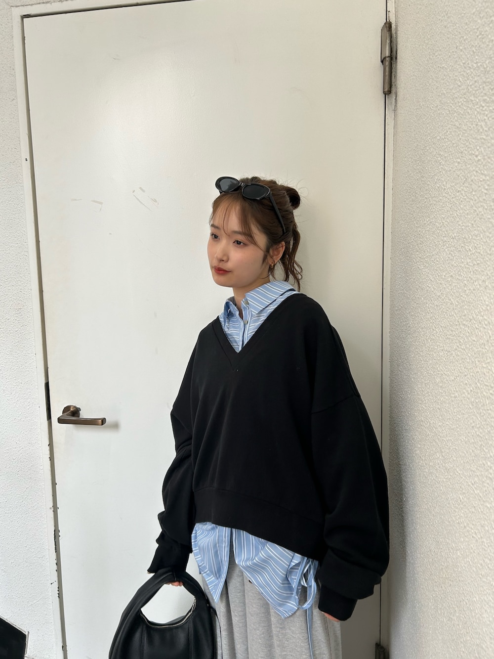 ブラック系のスウェット、ブルー系のシャツ/ブラウス、ブラック系のハンドバッグを着用したレディースの春コーディネートの6枚目の写真