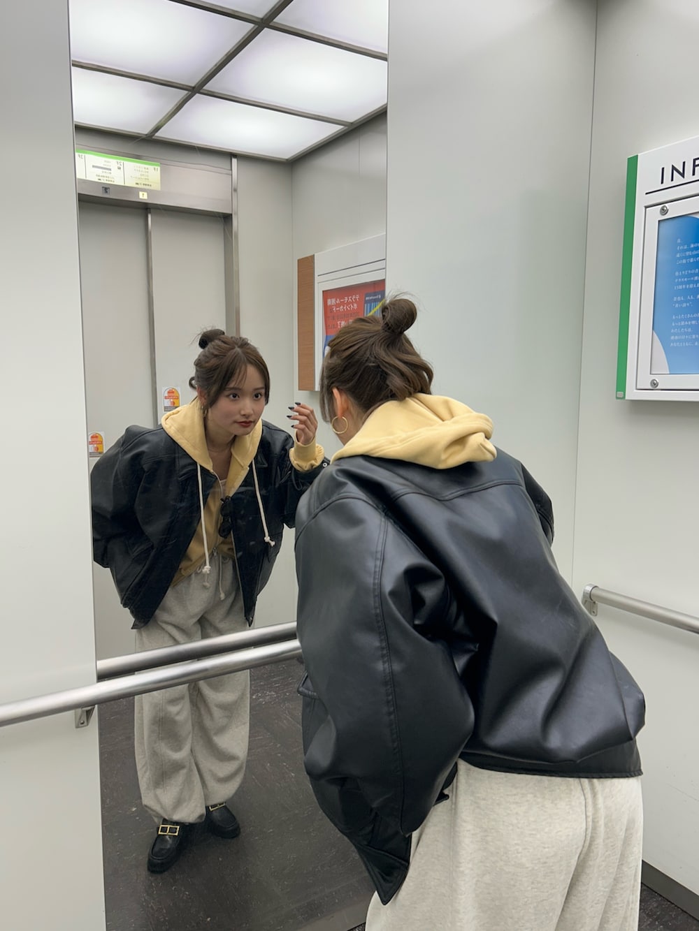 イエロー系のパーカー、ホワイト系のスウェットパンツ、ブラック系のブルゾンを着用したレディースの冬コーディネートの9枚目の写真