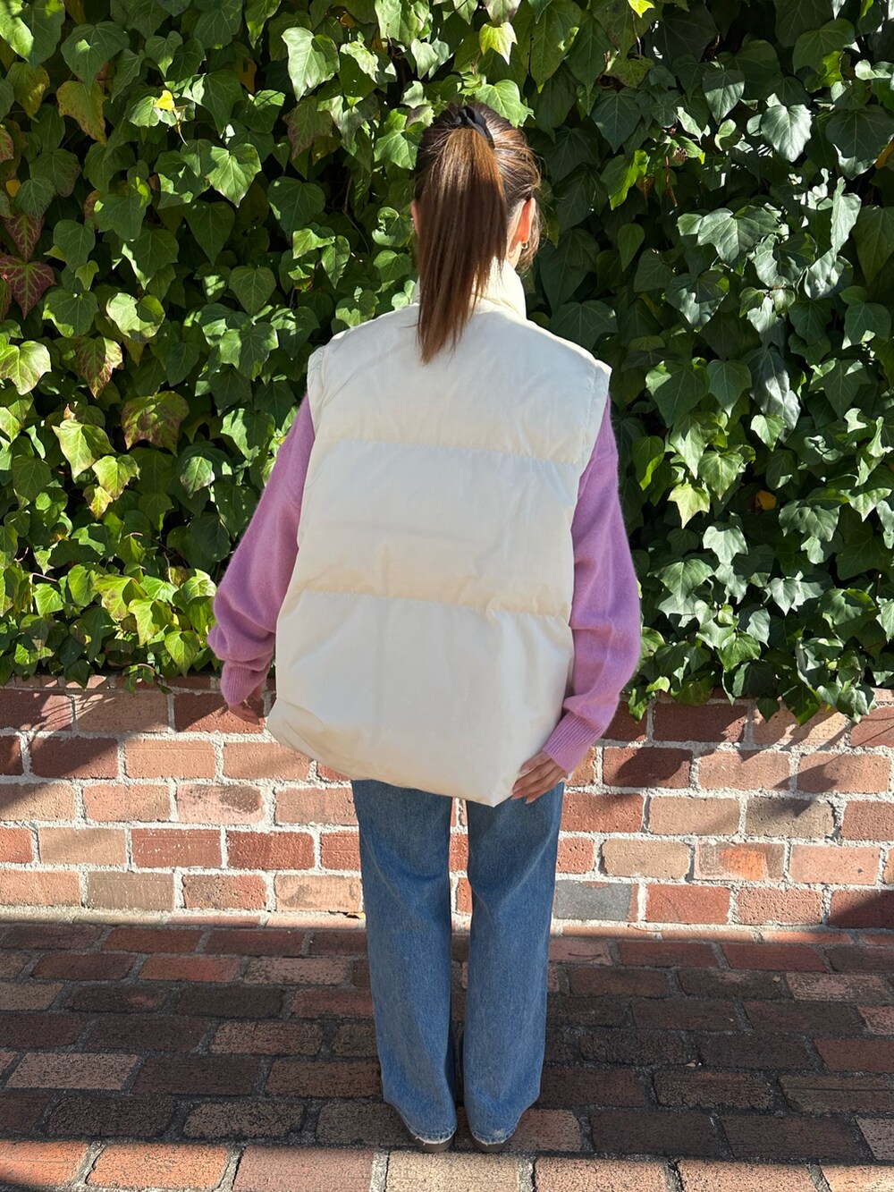 ブルー系のデニムパンツ、ピンク系のニット/セーター、ホワイト系のダウンジャケット/コートを着用したレディースの冬コーディネートの5枚目の写真