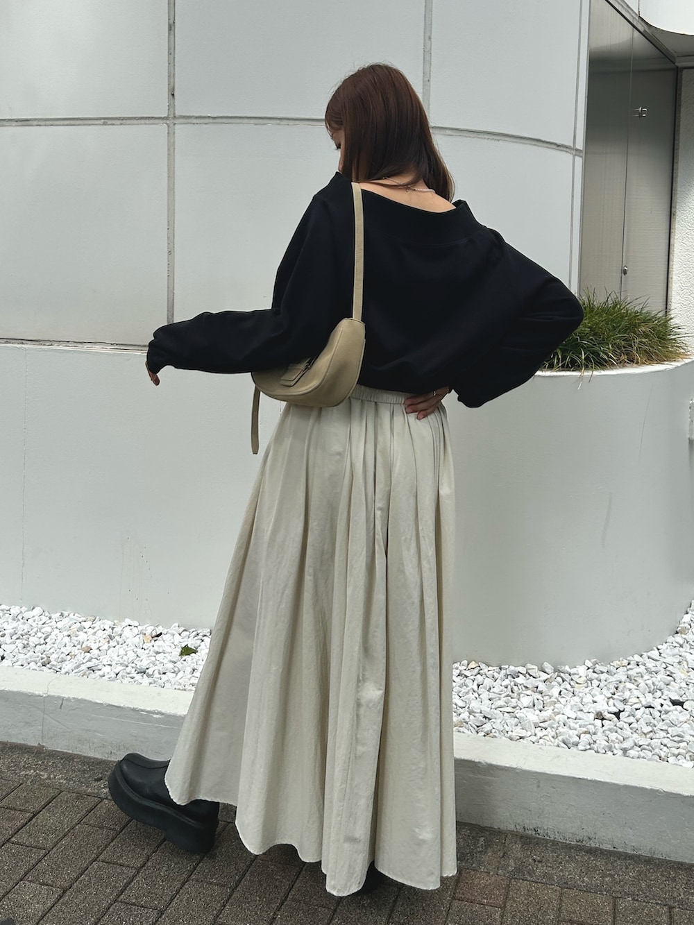 ブラック系のスウェット、ホワイト系のスカート、ブラック系のブーツを着用したレディースの秋コーディネートの4枚目の写真