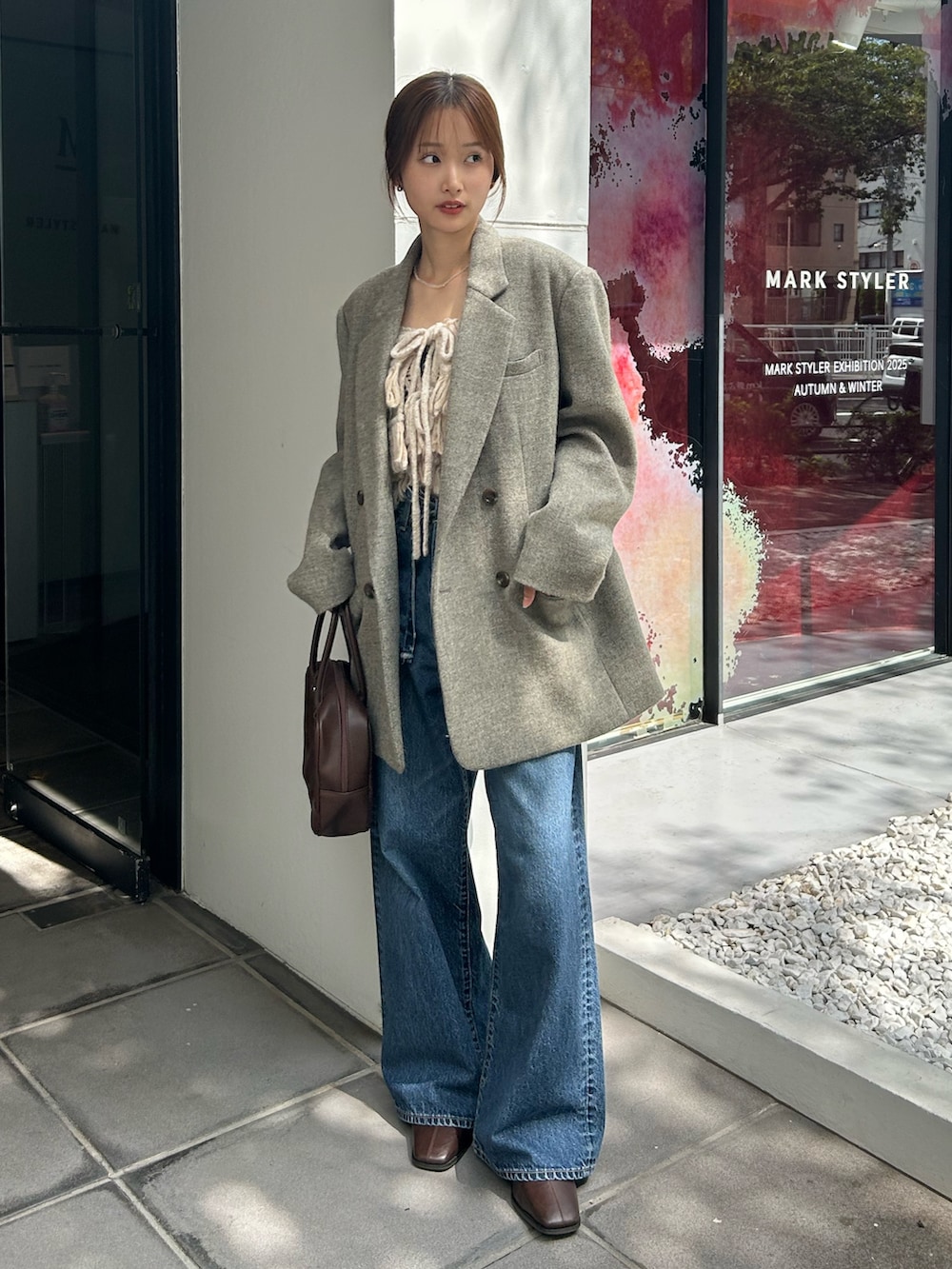 グレー系のテーラードジャケット、ホワイト系のニット/セーター、ブルー系のデニムパンツを着用したレディースの秋コーディネートの4枚目の写真