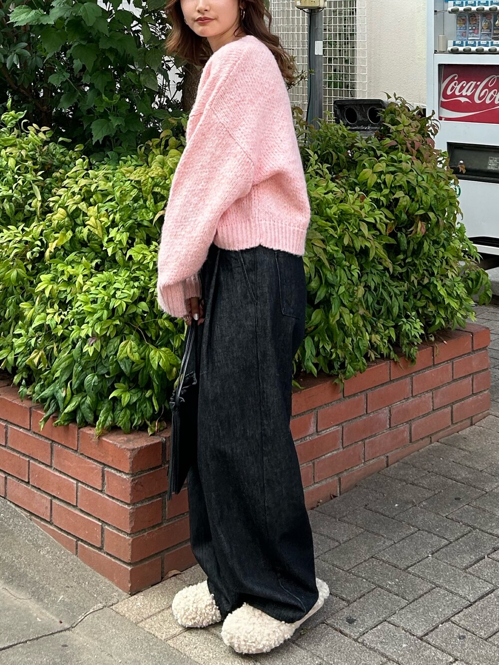 ピンク系のニット/セーター、ブラック系のデニムパンツ、ブラック系のショルダーバッグを着用したレディースの秋コーディネートの6枚目の写真
