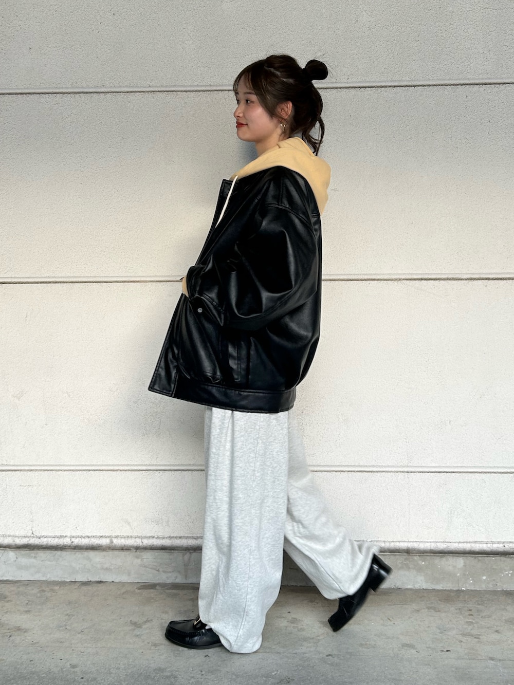 イエロー系のパーカー、ホワイト系のスウェットパンツ、ブラック系のブルゾンを着用したレディースの冬コーディネートの3枚目の写真