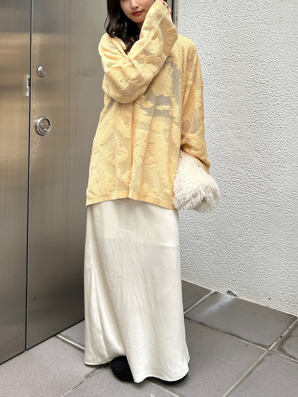 ブラック系のスリッポン、ホワイト系のハンドバッグ、イエロー系のニット/セーターを着用したレディースの冬コーディネートの7枚目の写真