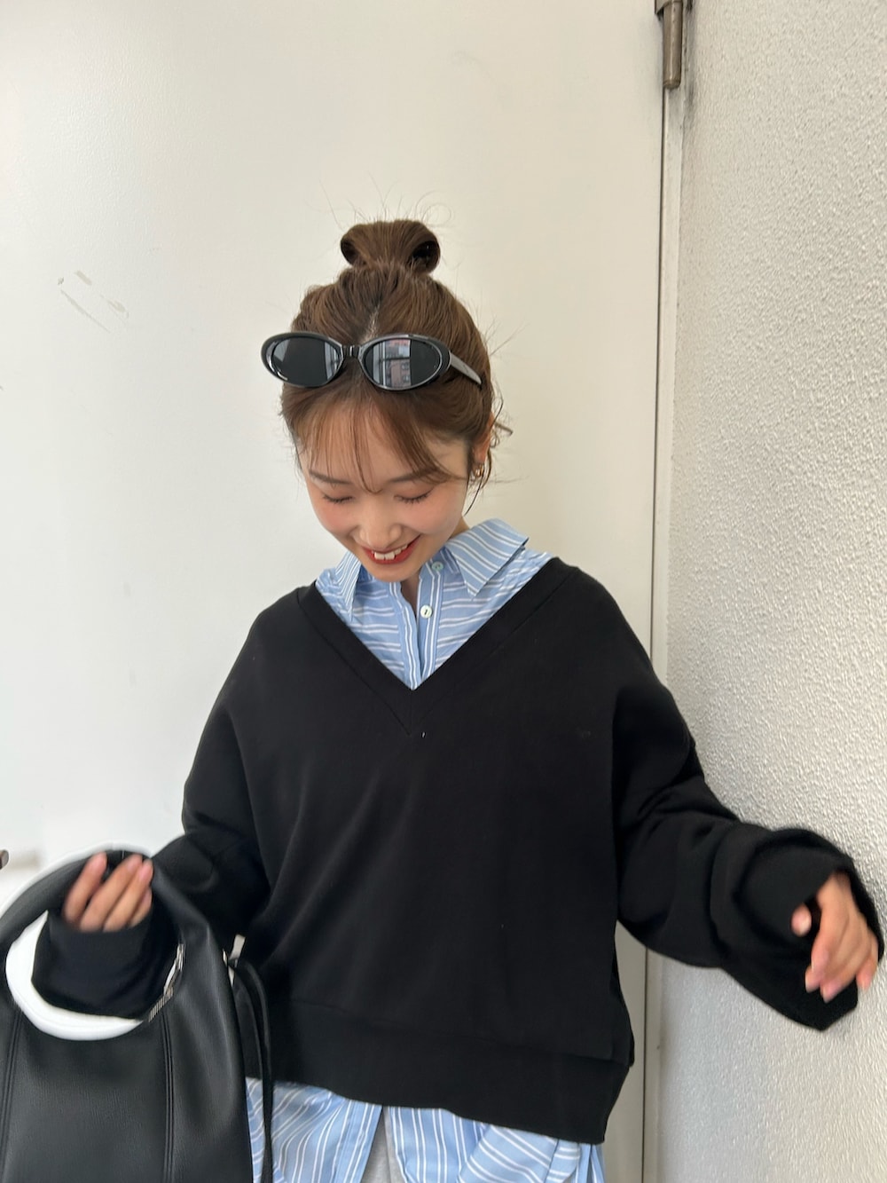 ブラック系のスウェット、ブルー系のシャツ/ブラウス、ブラック系のハンドバッグを着用したレディースの春コーディネートの5枚目の写真