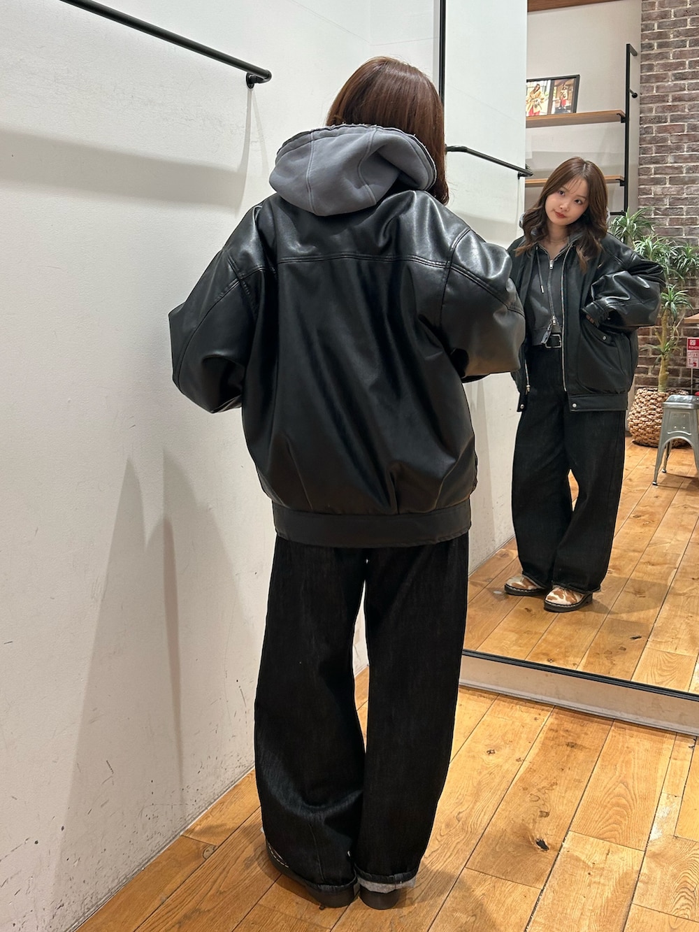 ブラック系のブルゾン、グレー系のパーカー、ブラック系のデニムパンツを着用したレディースの冬コーディネートの2枚目の写真