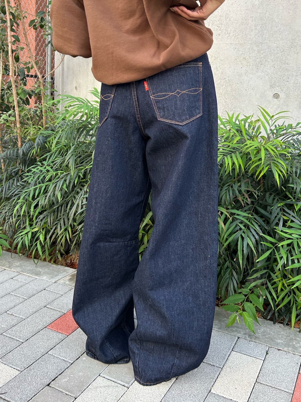 ブルー系のデニムパンツ、ブラック系のスリッポン、ブラウン系のスウェットを着用したレディースの冬コーディネートの9枚目の写真