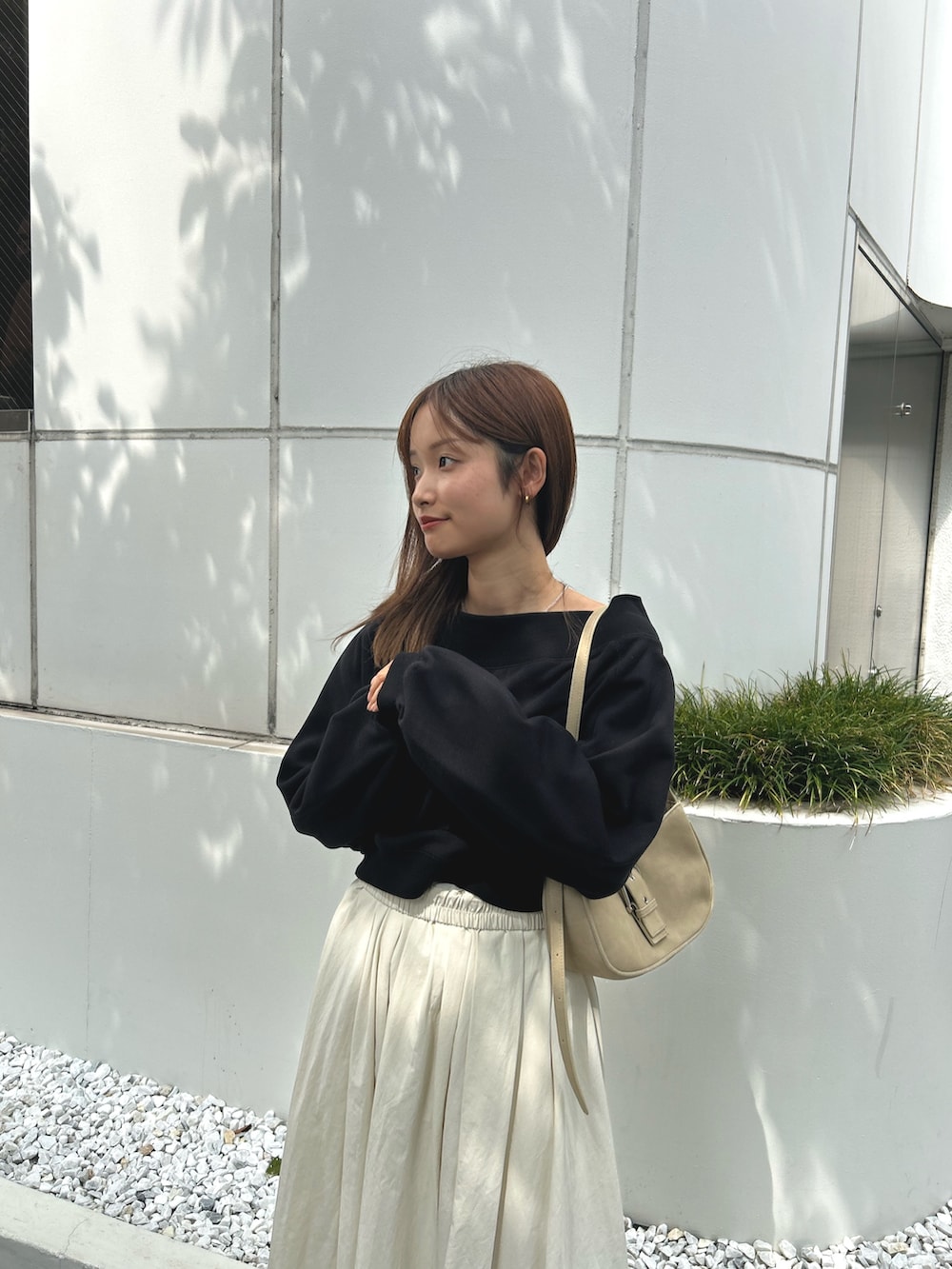 ブラック系のスウェット、ホワイト系のスカート、ブラック系のブーツを着用したレディースの秋コーディネートの5枚目の写真