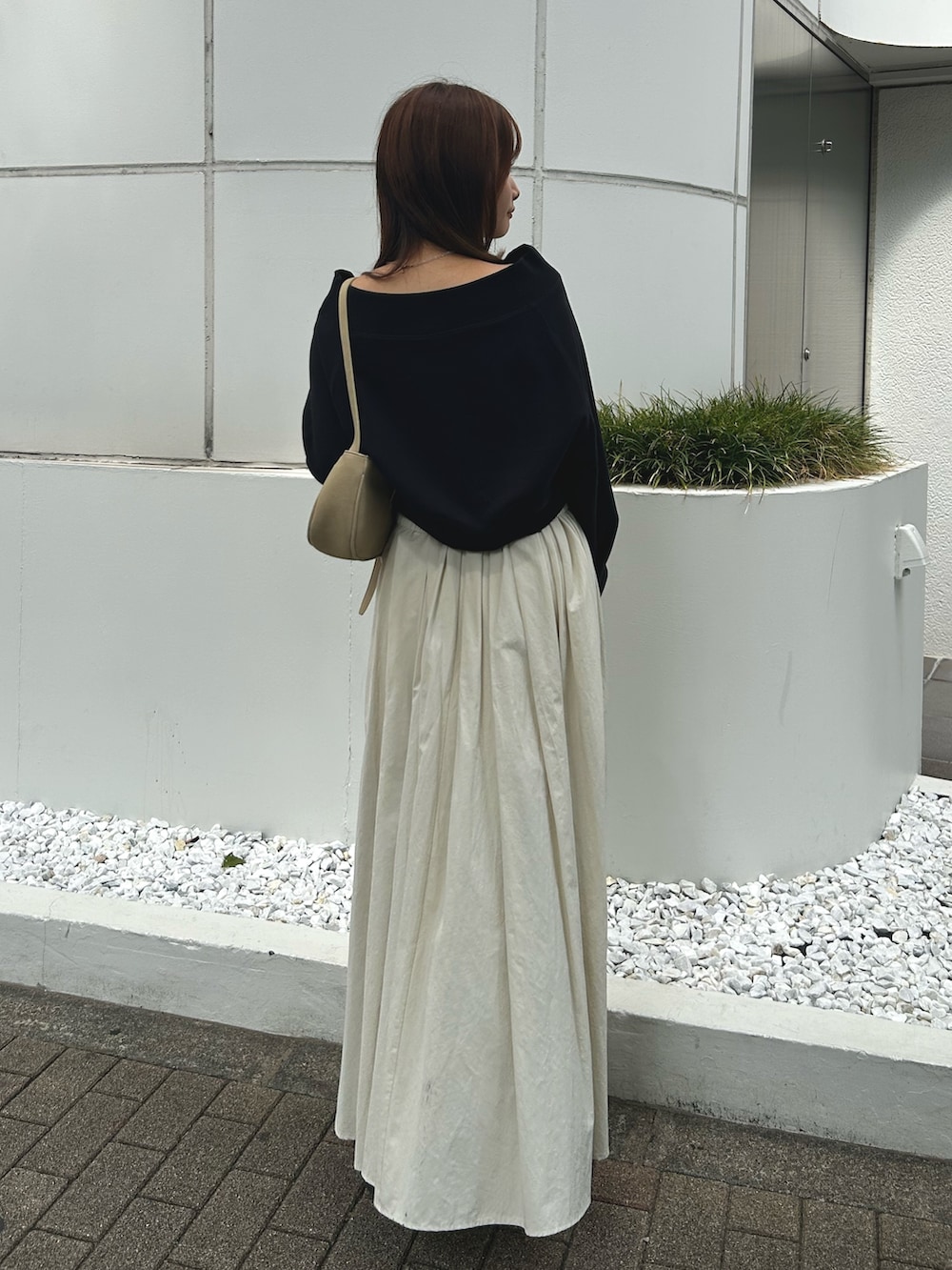 ブラック系のスウェット、ホワイト系のスカート、ブラック系のブーツを着用したレディースの秋コーディネートの3枚目の写真