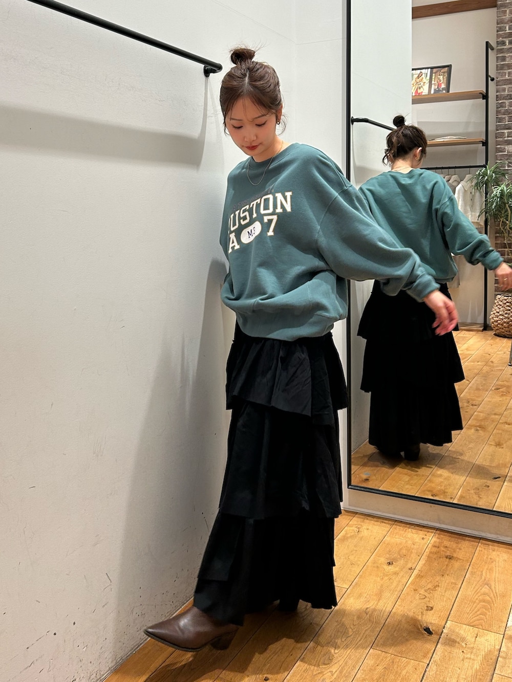 グリーン系のスウェット、ブラック系のスカートを着用したレディースの冬コーディネートの3枚目の写真