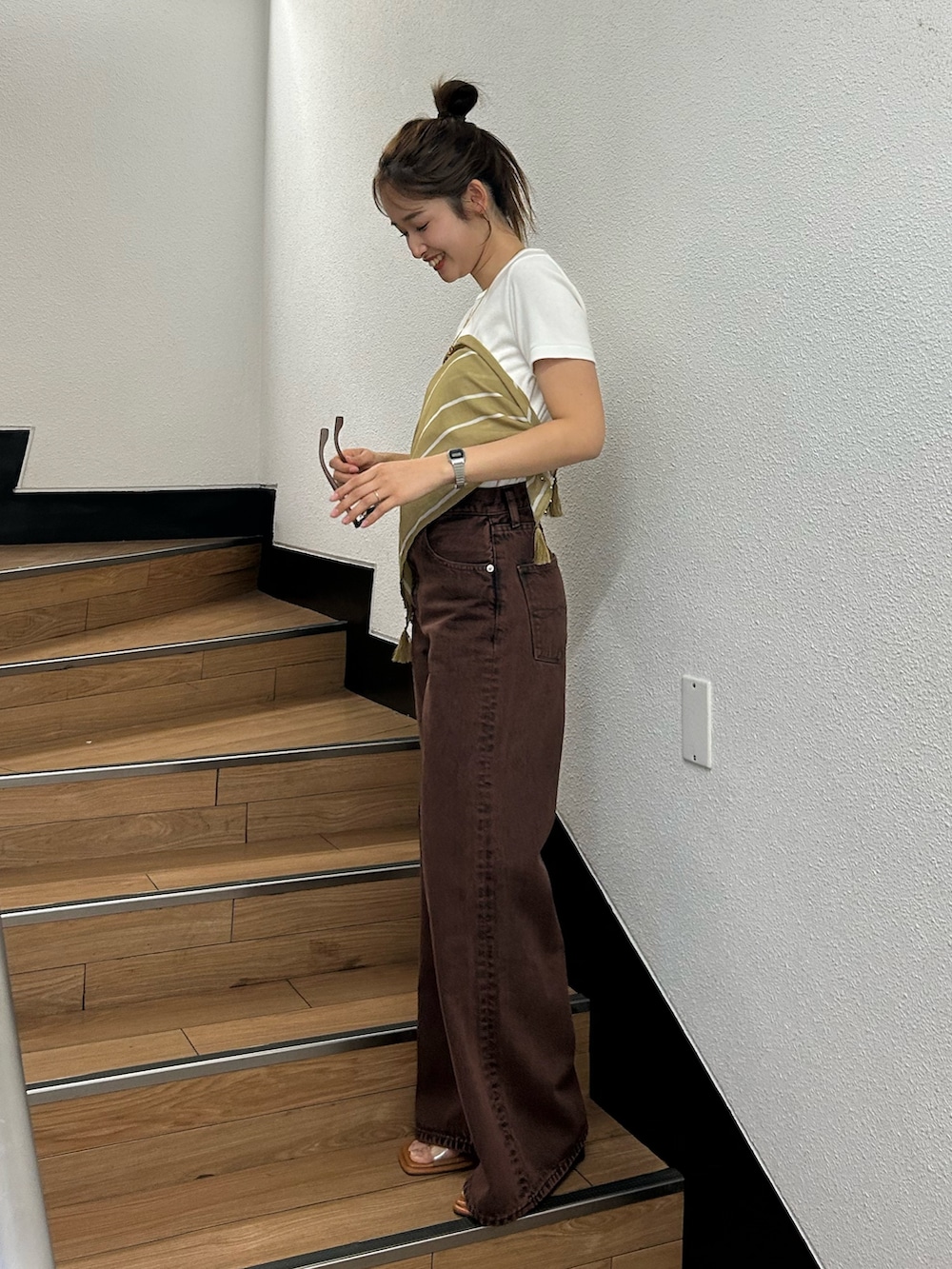 ブラウン系のデニムパンツ、ホワイト系のTシャツ/カットソー、イエロー系のバンダナ/スカーフを着用したレディースの春コーディネートの4枚目の写真