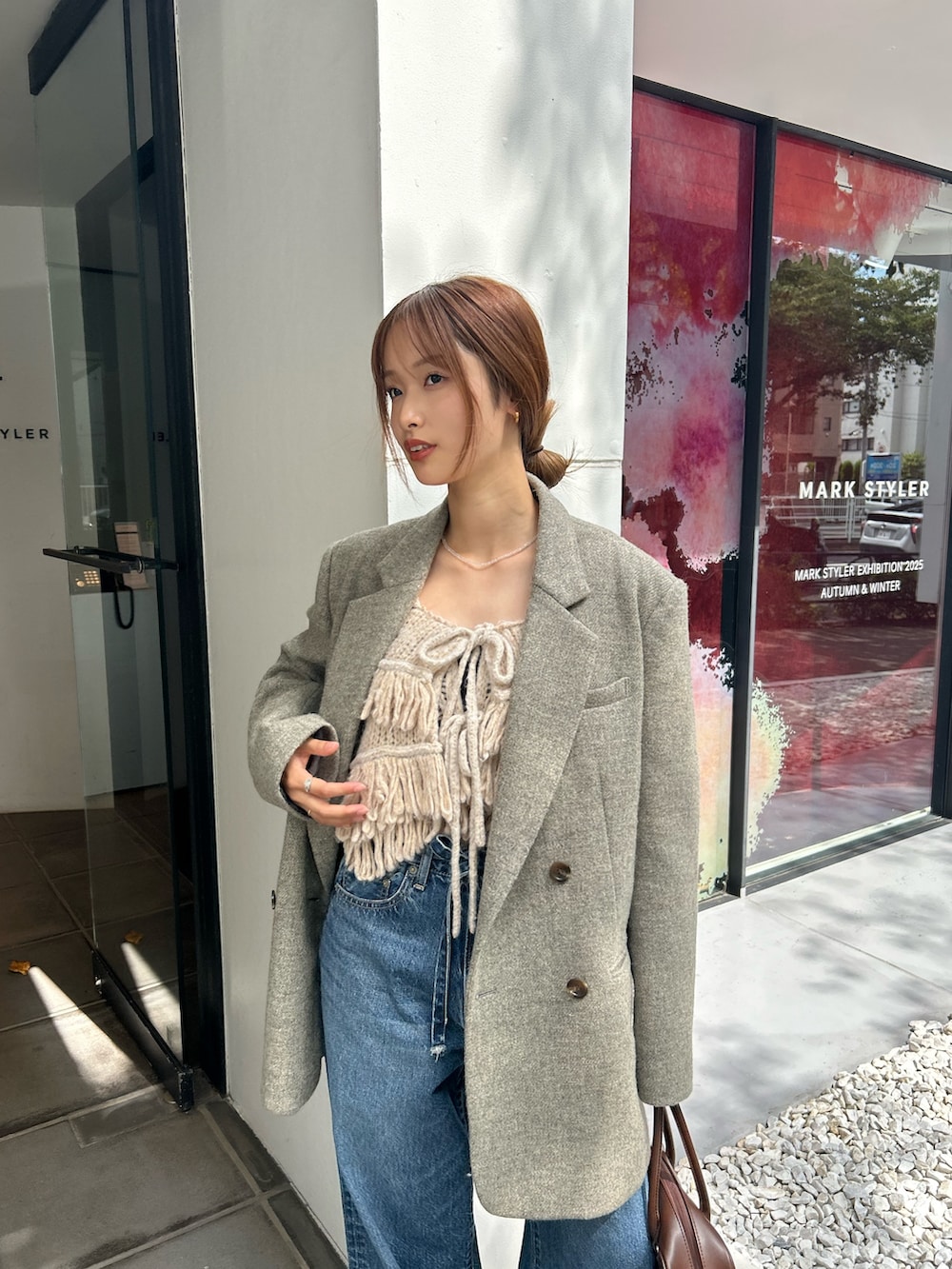 グレー系のテーラードジャケット、ホワイト系のニット/セーター、ブルー系のデニムパンツを着用したレディースの秋コーディネートの2枚目の写真