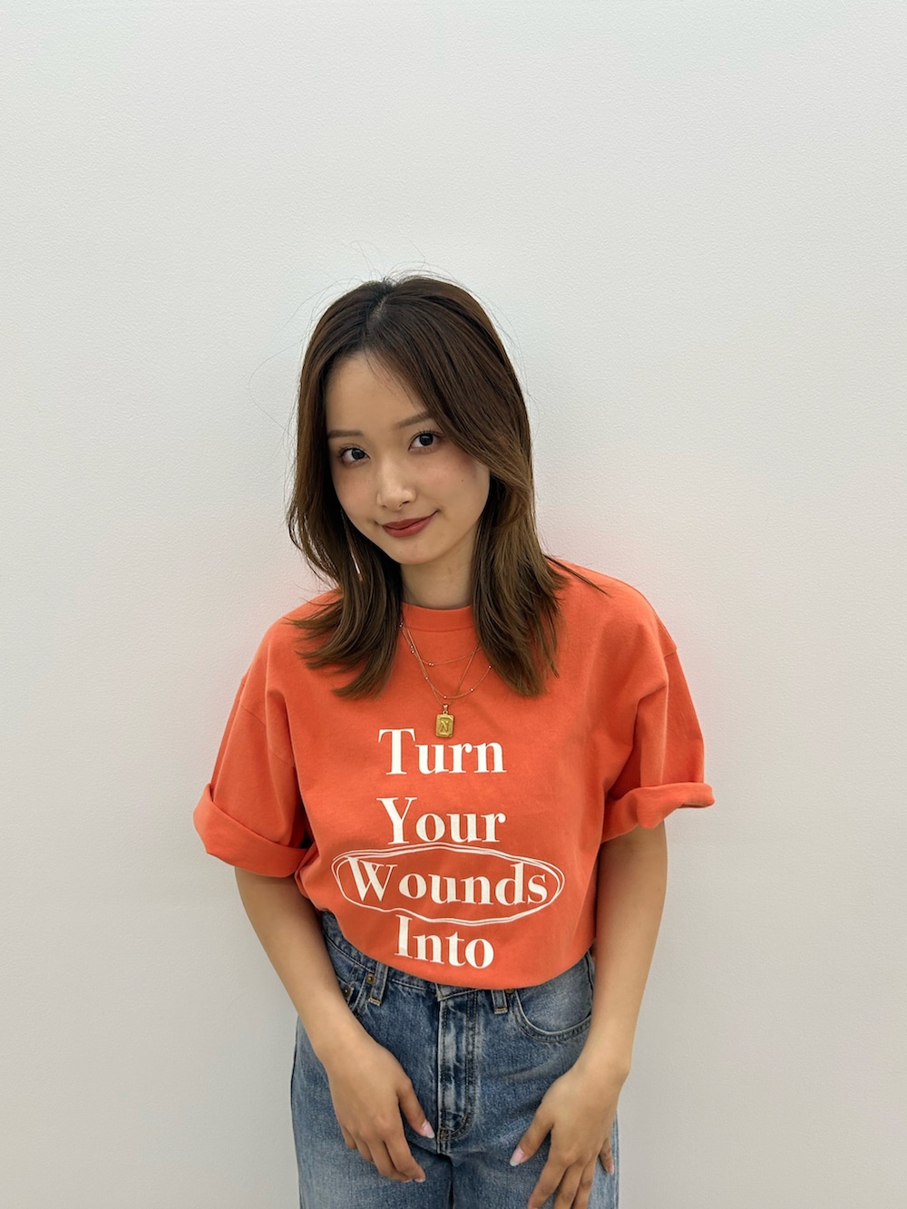 ブルー系のデニムパンツ、オレンジ系のTシャツ/カットソー、ブラック系のサンダルを着用したレディースの春コーディネートの6枚目の写真
