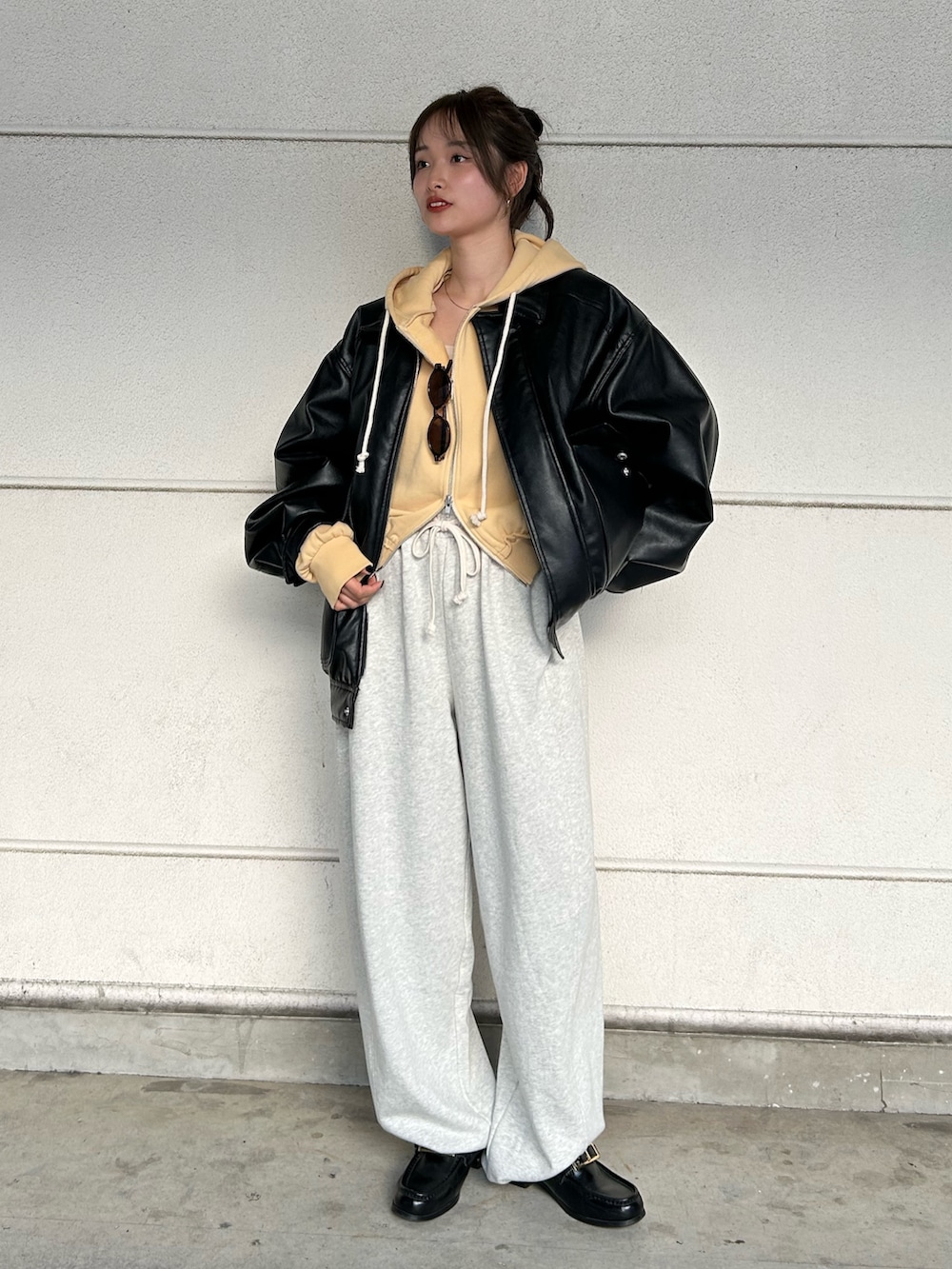 イエロー系のパーカー、ホワイト系のスウェットパンツ、ブラック系のブルゾンを着用したレディースの冬コーディネートの2枚目の写真