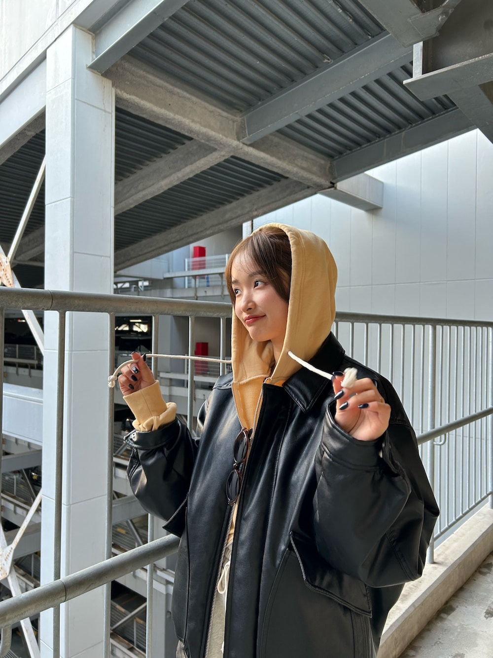 イエロー系のパーカー、ホワイト系のスウェットパンツ、ブラック系のブルゾンを着用したレディースの冬コーディネートの7枚目の写真