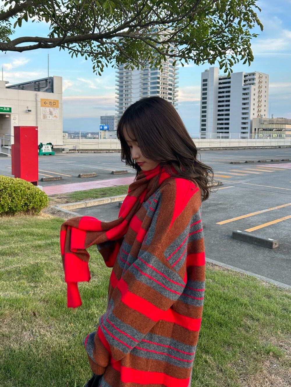 レッド系のニット/セーター、ブルー系のデニムパンツ、ブラック系のショルダーバッグを着用したレディースの秋コーディネートの5枚目の写真