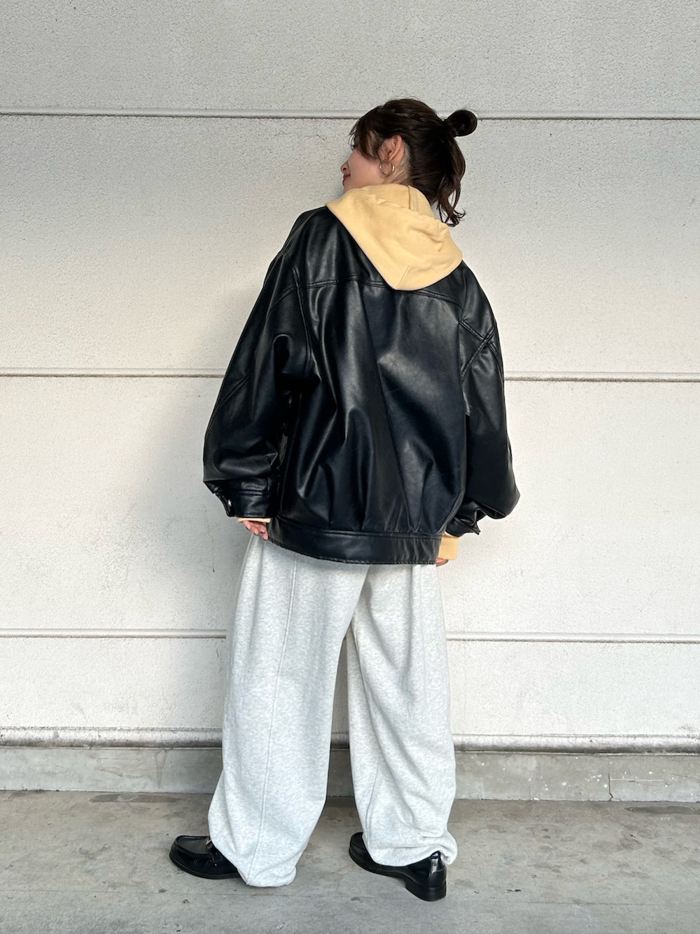 イエロー系のパーカー、ホワイト系のスウェットパンツ、ブラック系のブルゾンを着用したレディースの冬コーディネートの5枚目の写真