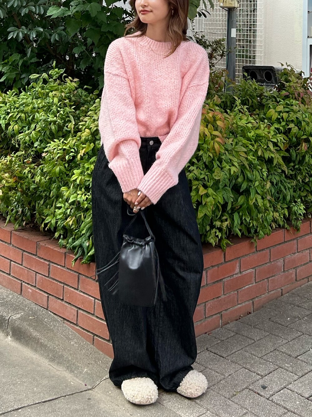 ピンク系のニット/セーター、ブラック系のデニムパンツ、ブラック系のショルダーバッグを着用したレディースの秋コーディネートの5枚目の写真