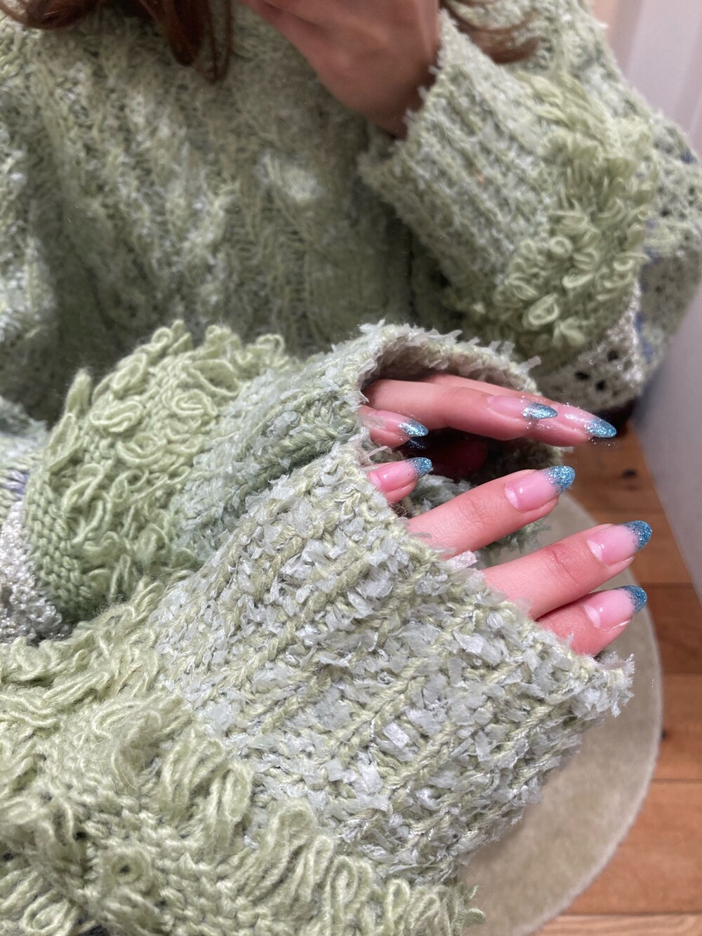 グリーン系のニット/セーター、ブルー系のデニムパンツ、ブラウン系のブーツを着用したレディースの冬コーディネートの6枚目の写真
