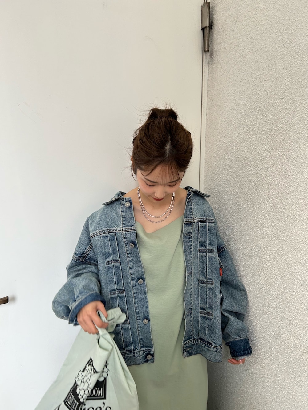 グリーン系のトートバッグ、ブルー系のスニーカー、ブルー系のデニムジャケットを着用したレディースの春コーディネートの6枚目の写真