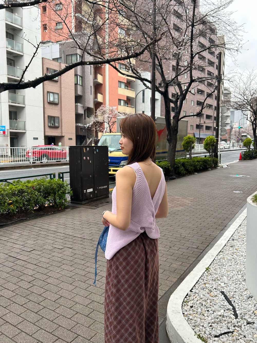 ブルー系のハンドバッグ、ブラウン系のスカート、シルバー系のネックレスを着用したレディースの春コーディネートの5枚目の写真