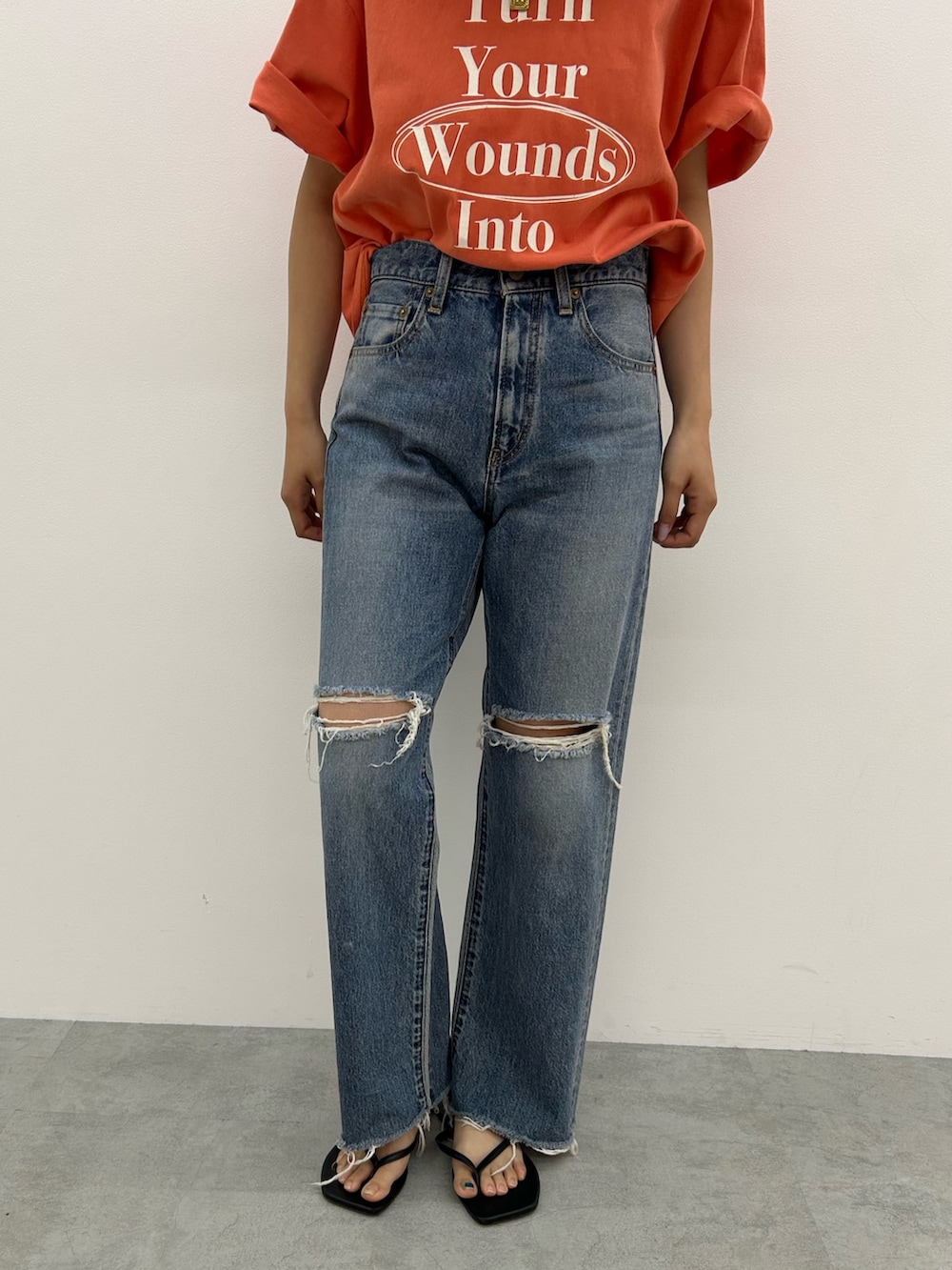 ブルー系のデニムパンツ、オレンジ系のTシャツ/カットソー、ブラック系のサンダルを着用したレディースの春コーディネートの5枚目の写真