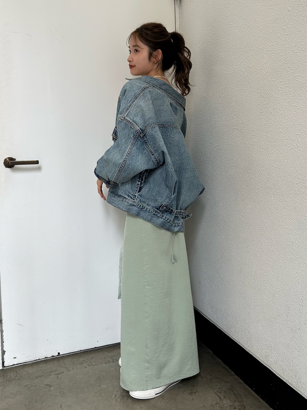 グリーン系のトートバッグ、ブルー系のスニーカー、ブルー系のデニムジャケットを着用したレディースの春コーディネートの3枚目の写真