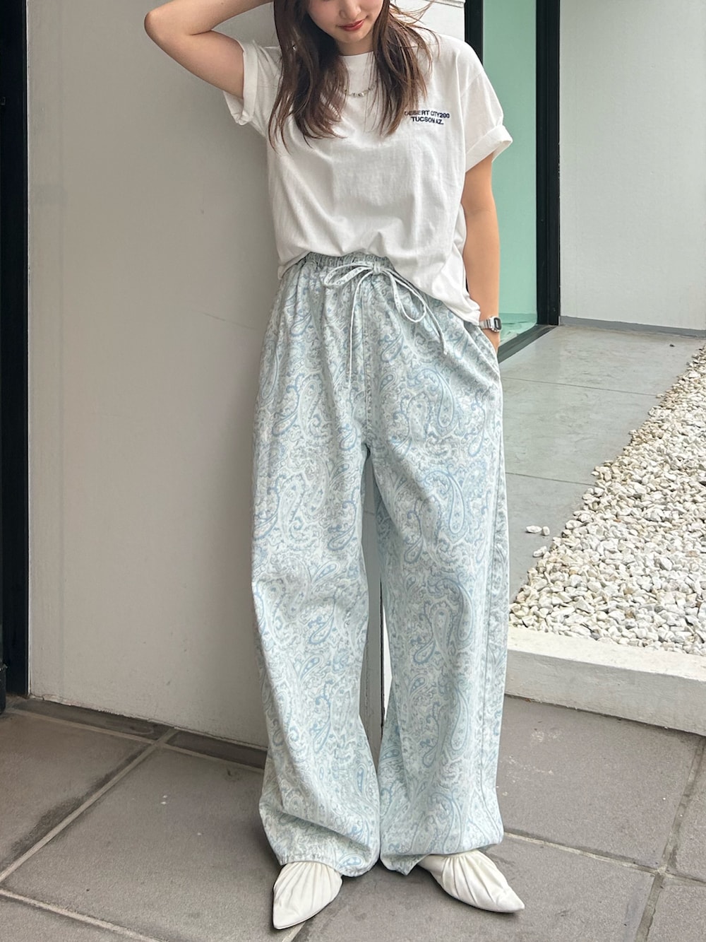 ブルー系のデニムパンツ、ホワイト系のパンプス、ホワイト系のTシャツ/カットソーを着用したレディースの春コーディネートの2枚目の写真