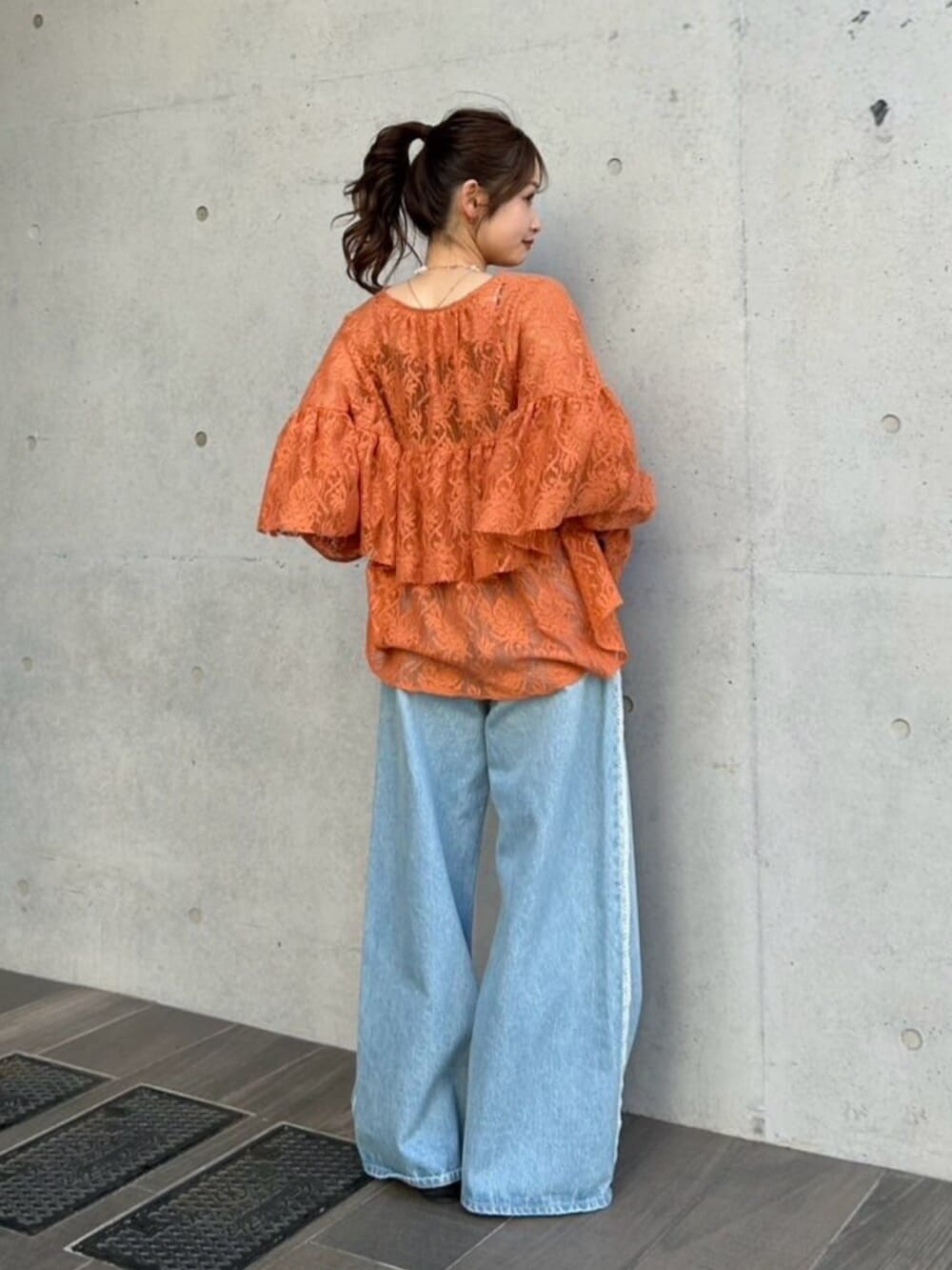 ブルー系のデニムパンツ、ブラック系のパンプス、オレンジ系のシャツ/ブラウスを着用したレディースの冬コーディネートの3枚目の写真