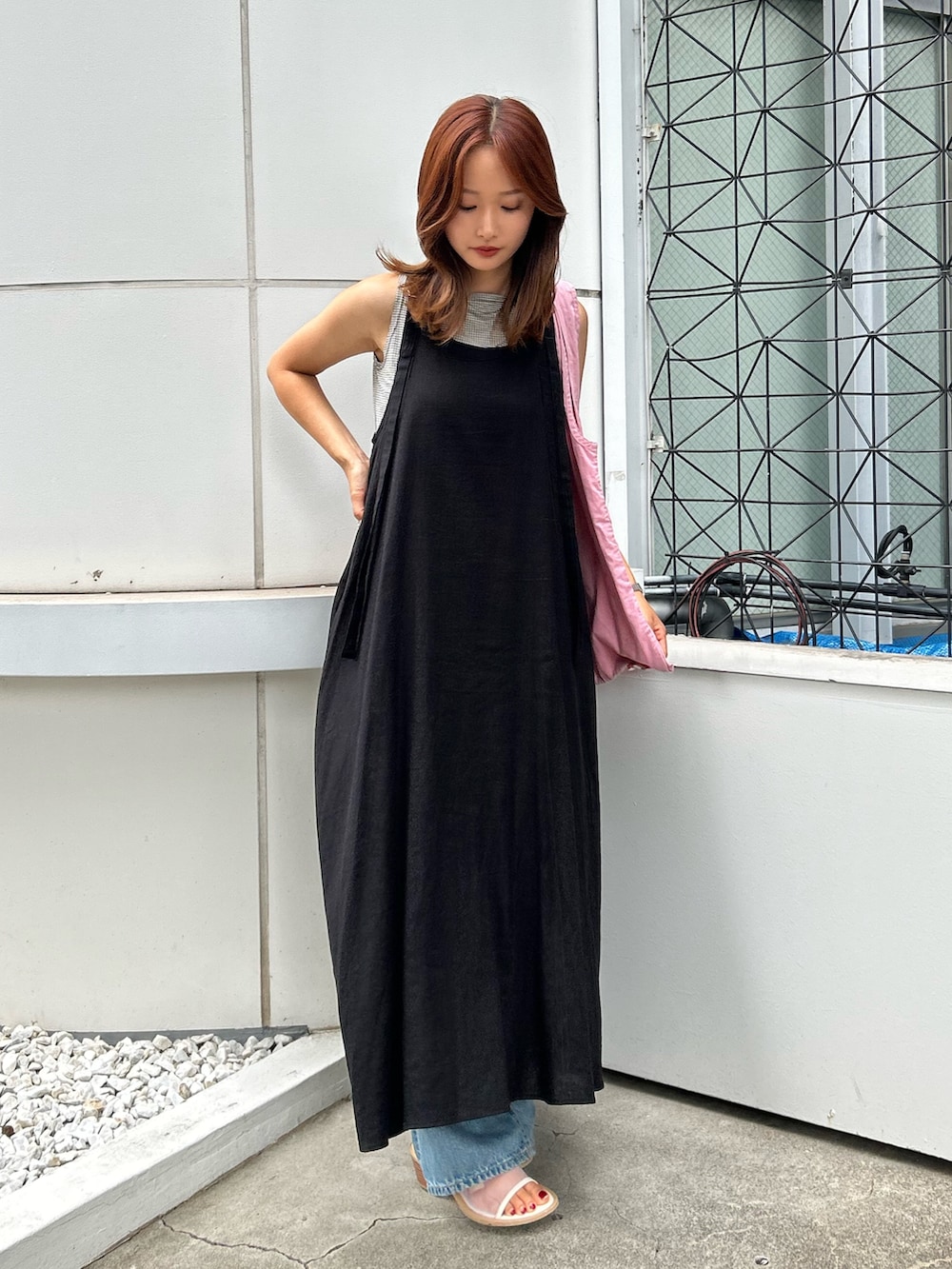 ブラック系のワンピース、ホワイト系のサンダル、ブルー系のデニムパンツを着用したレディースの夏コーディネートの2枚目の写真