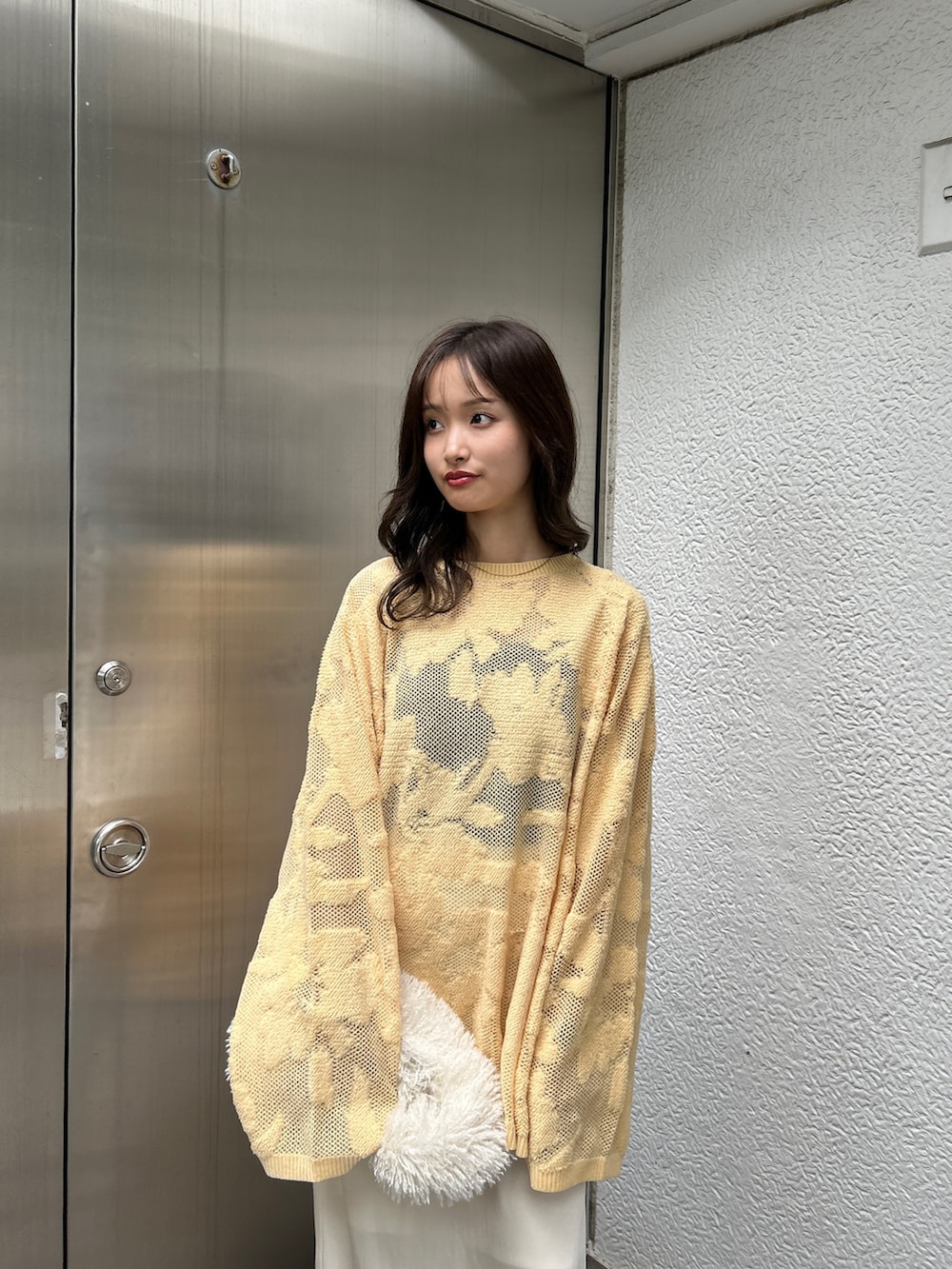 ブラック系のスリッポン、ホワイト系のハンドバッグ、イエロー系のニット/セーターを着用したレディースの冬コーディネートの6枚目の写真