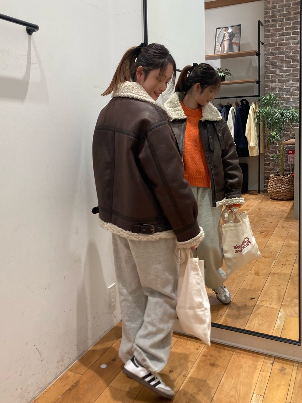 グレー系のスウェットパンツ、レッド系のトートバッグ、ブラウン系のブルゾンを着用したレディースの冬コーディネートの5枚目の写真