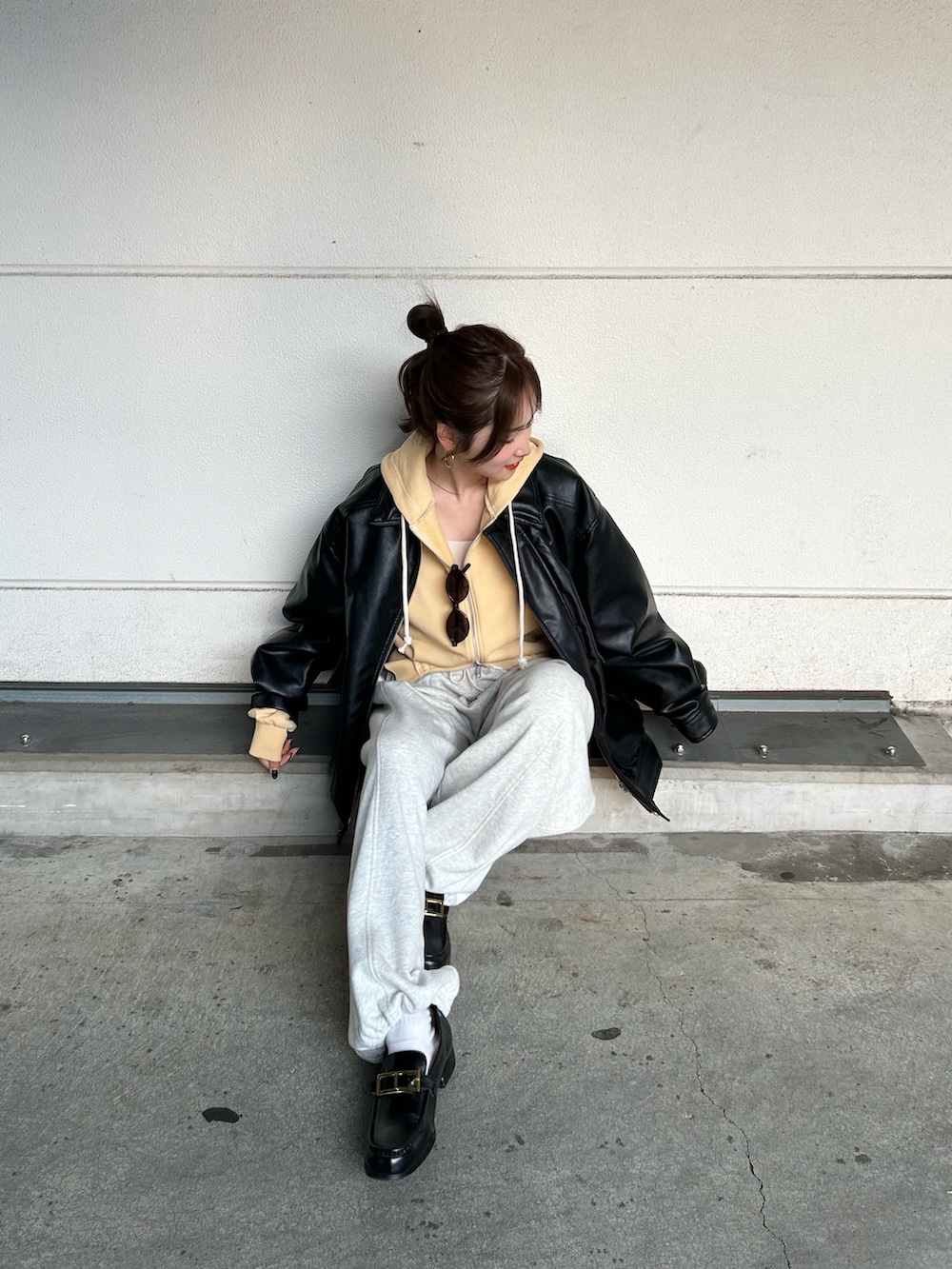 イエロー系のパーカー、ホワイト系のスウェットパンツ、ブラック系のブルゾンを着用したレディースの冬コーディネートの6枚目の写真