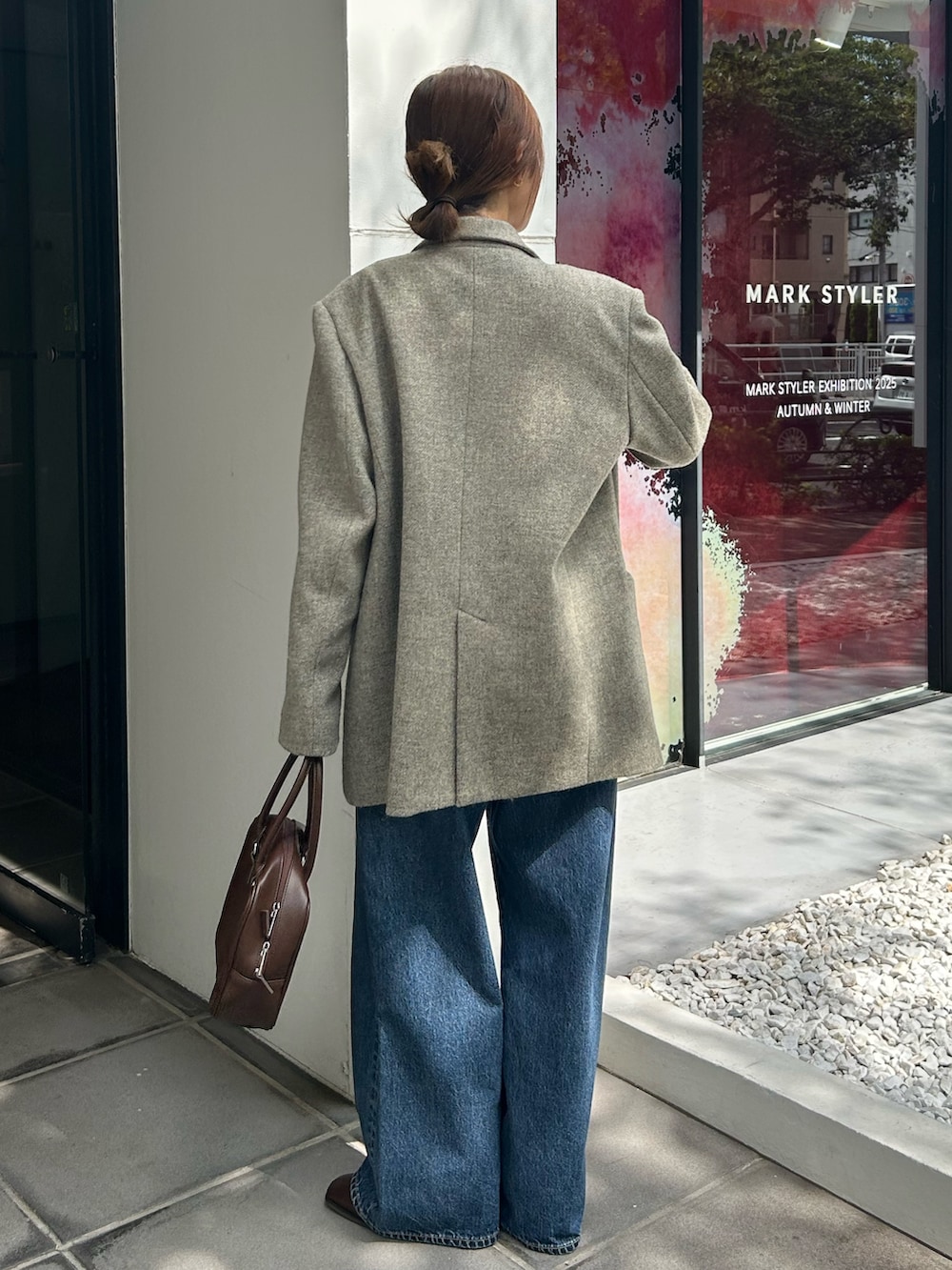 グレー系のテーラードジャケット、ホワイト系のニット/セーター、ブルー系のデニムパンツを着用したレディースの秋コーディネートの6枚目の写真