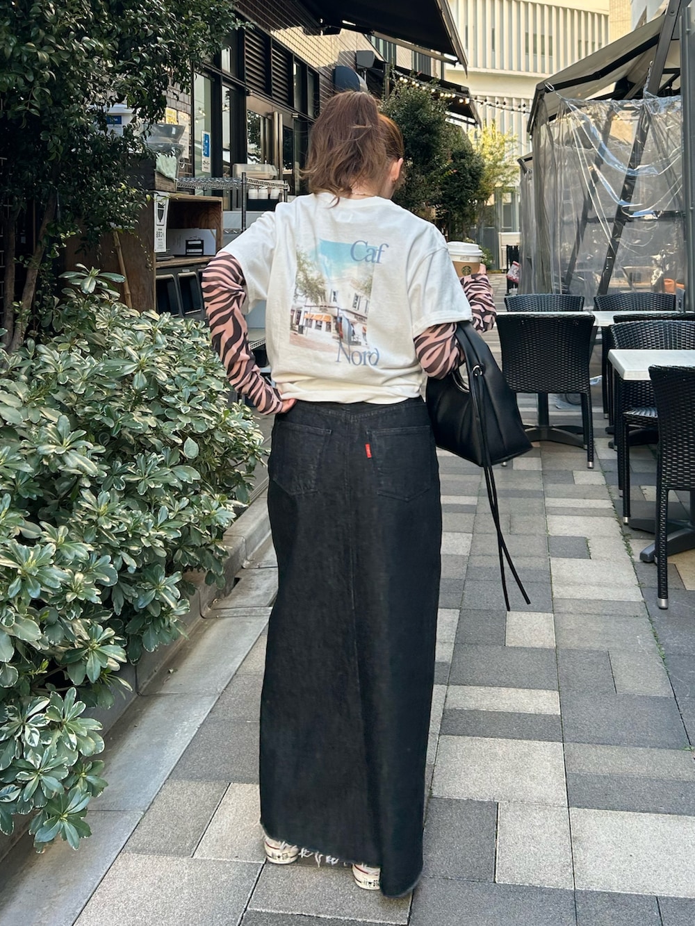 ブラック系のTシャツ/カットソー、ホワイト系のTシャツ/カットソー、ブラック系のスカートを着用したレディースの春コーディネートの4枚目の写真