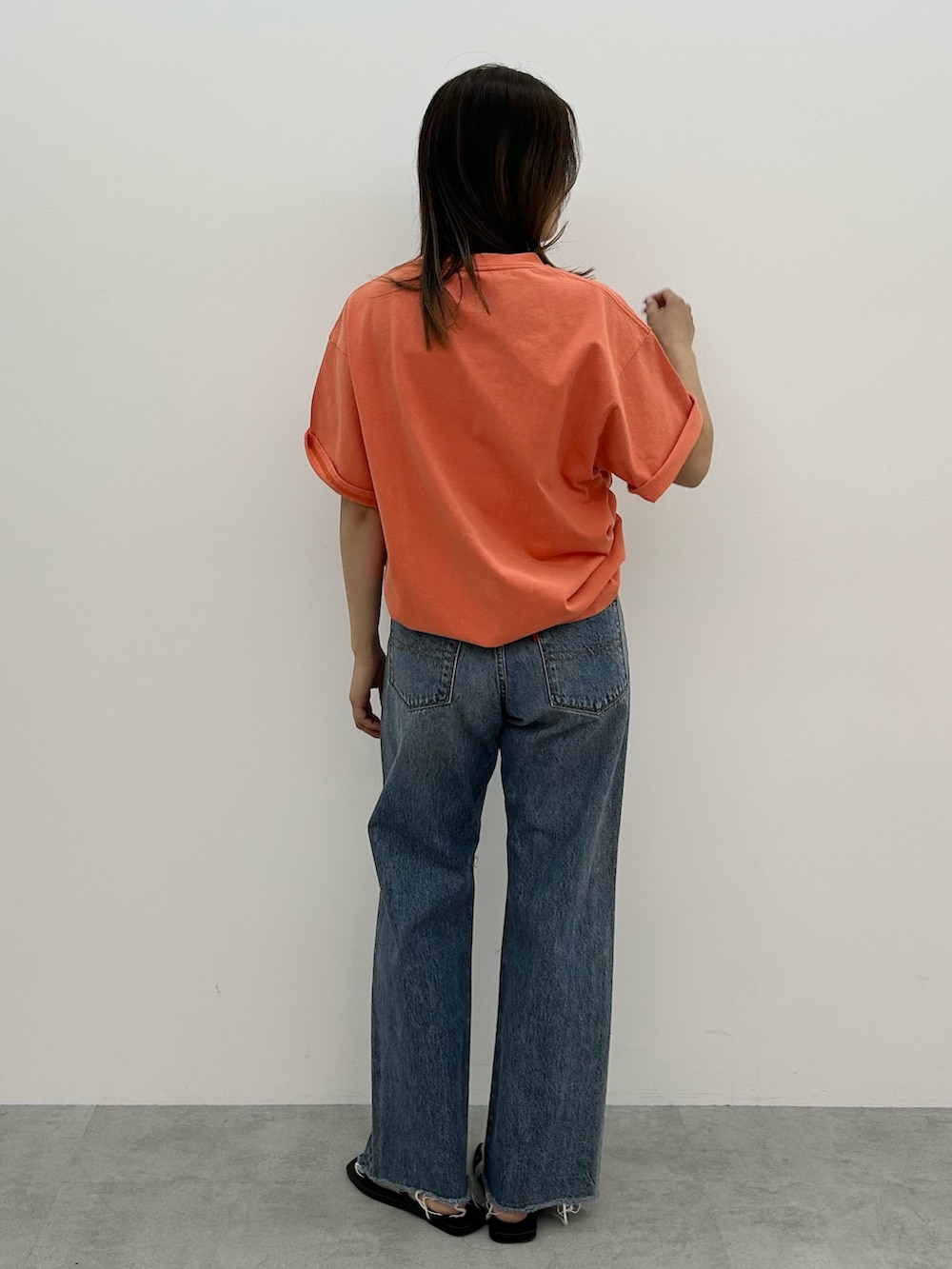 ブルー系のデニムパンツ、オレンジ系のTシャツ/カットソー、ブラック系のサンダルを着用したレディースの春コーディネートの4枚目の写真
