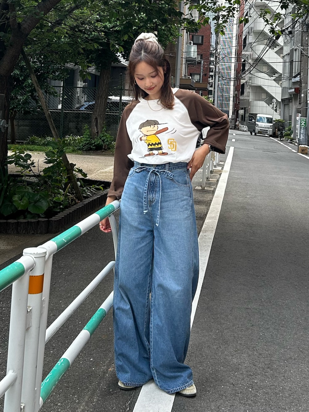 ブルー系のデニムパンツ、ベージュ系のローファー、ブラウン系のTシャツ/カットソーを着用したレディースの夏コーディネートの2枚目の写真
